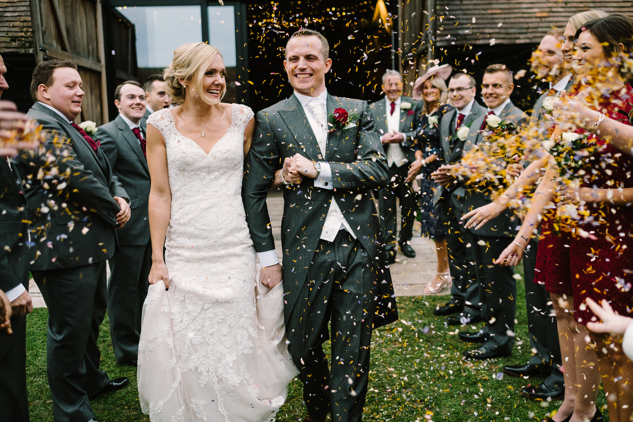 The bride and groom in confetti outside Lains Barn Wedding Venue, Oxfordshire