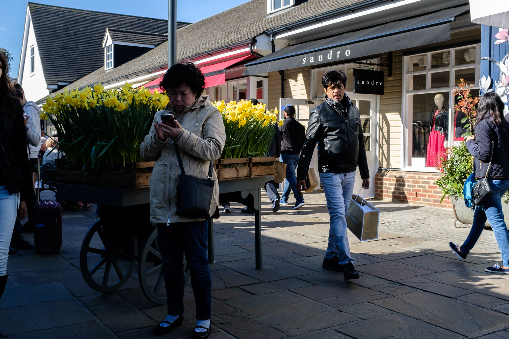 A woman checks her phone at Bicester Village Outlet Centre