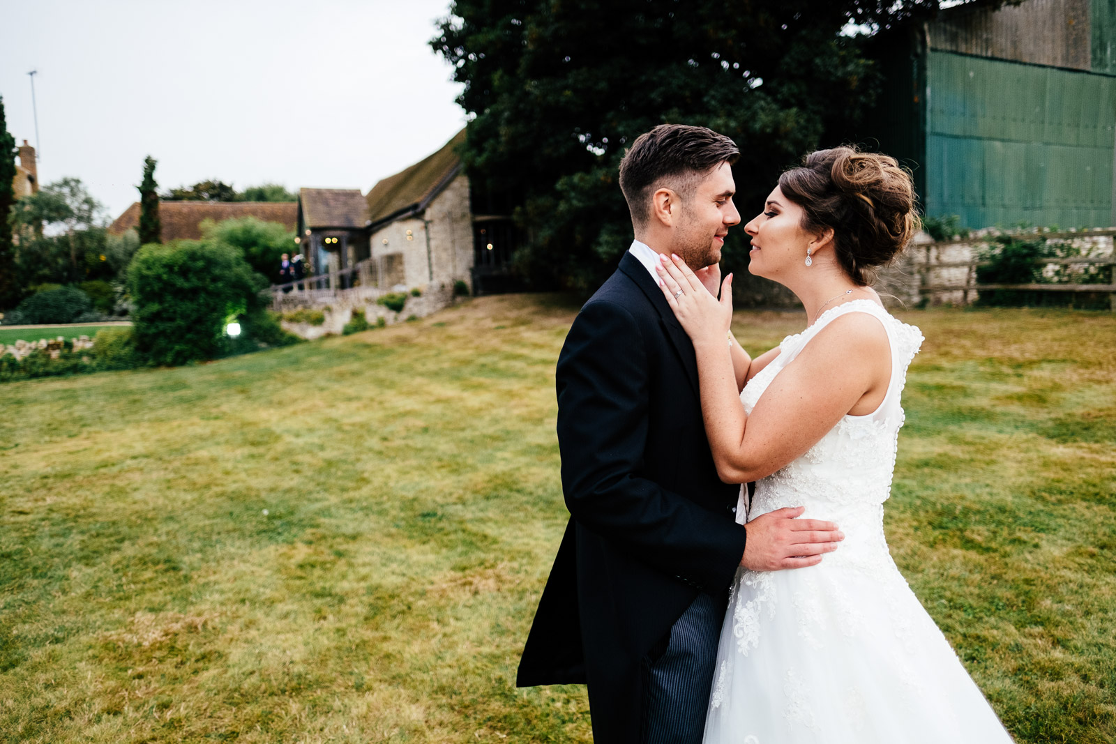A bride and groom embrace outside Notley Tythe Barn, Buckinghamshire. Photo by Sam and Steve Photography
