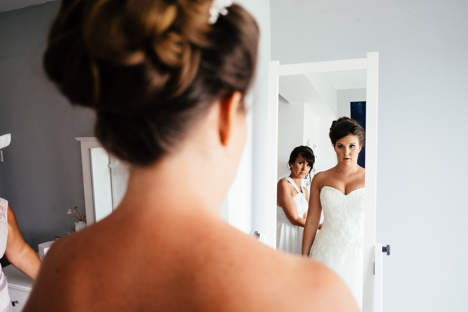 A bride checks her reflection in a mirror. Photo by Sam and Steve Photography