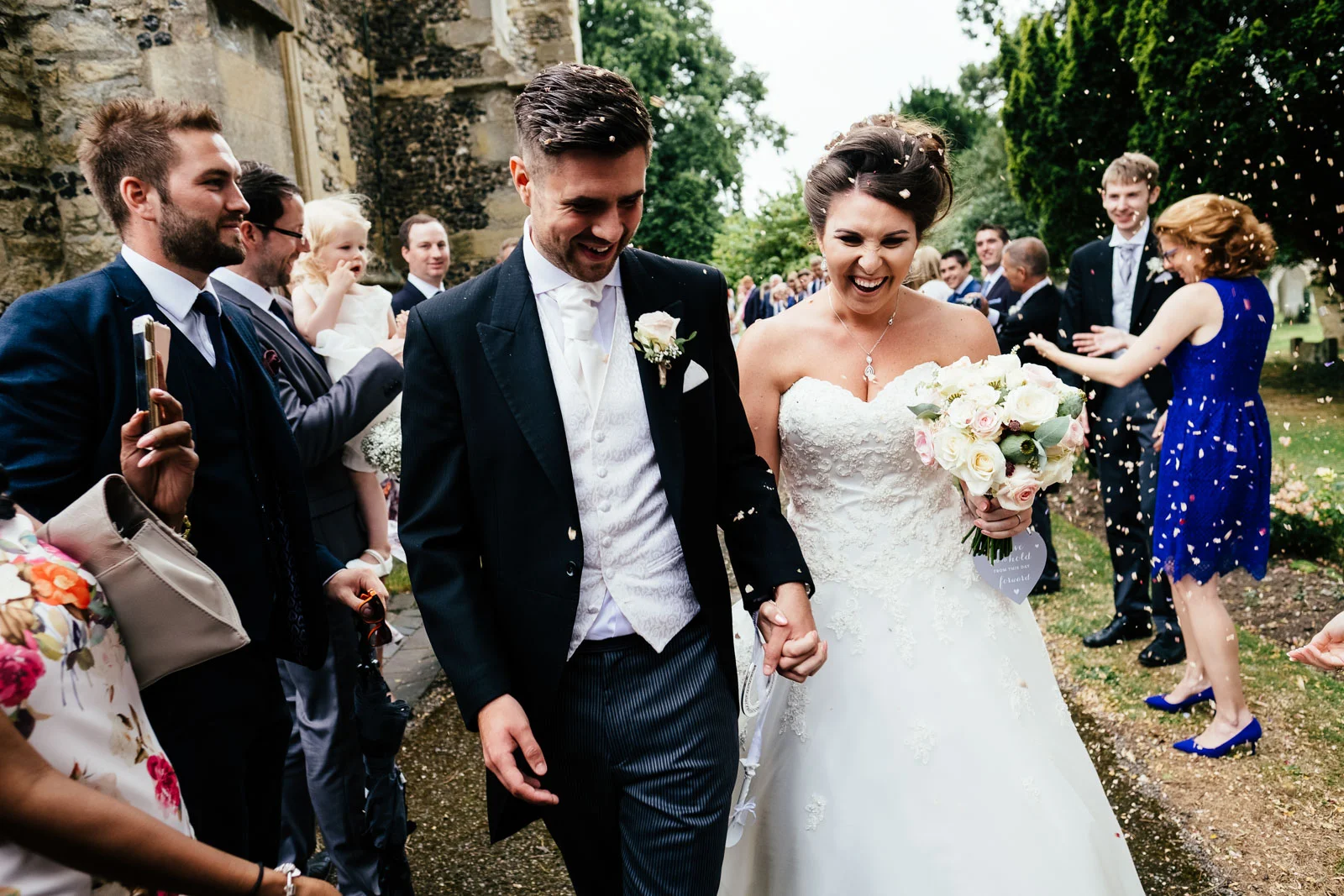 A bride and groom in confetti at Chinnor Church. Photo by Sam and Steve Photography