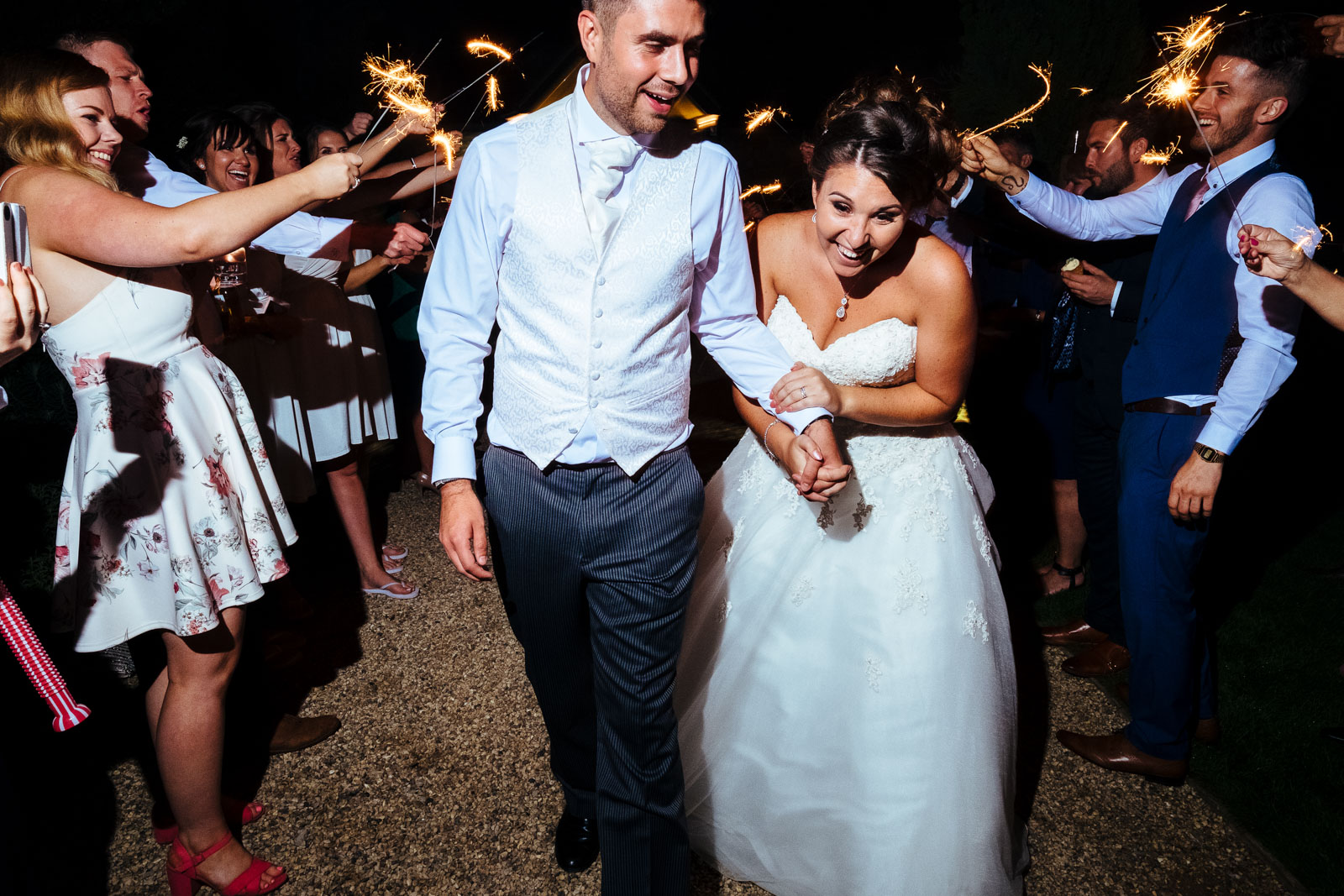 A bride and groom surrounded by sparklers at Notley Tythe Barn Wedding Venue