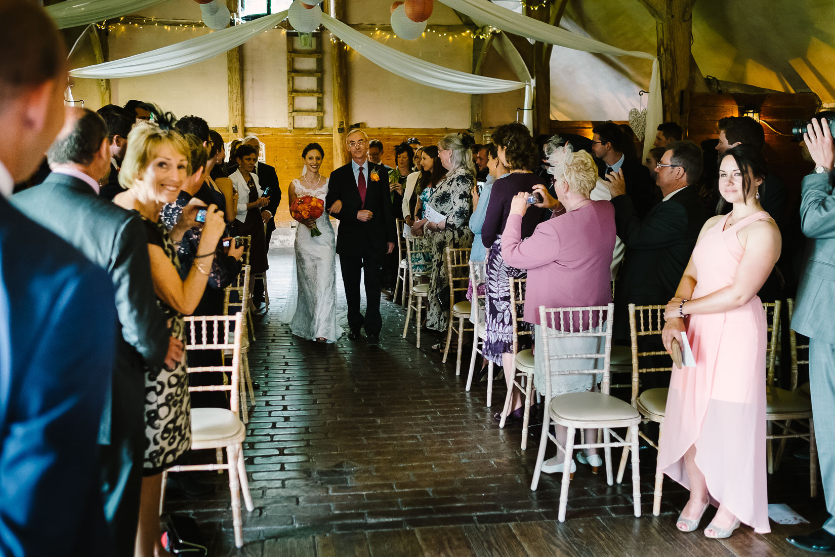 A bride and her father approaching a groom at Lains Barn Wedding Venue Oxfordshire