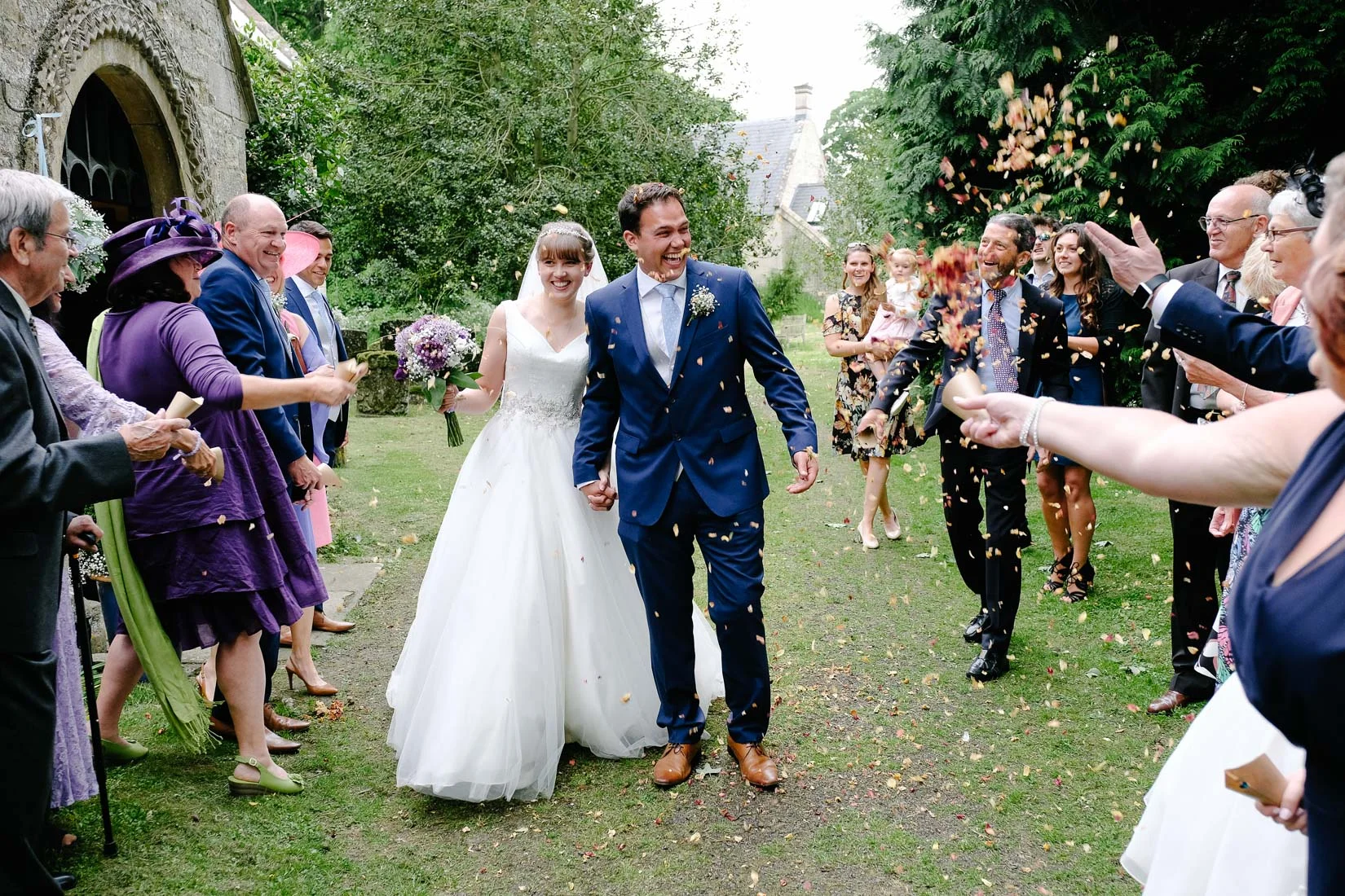 A bride and groom showered in Confetti outside All Saints Church, Mixbury