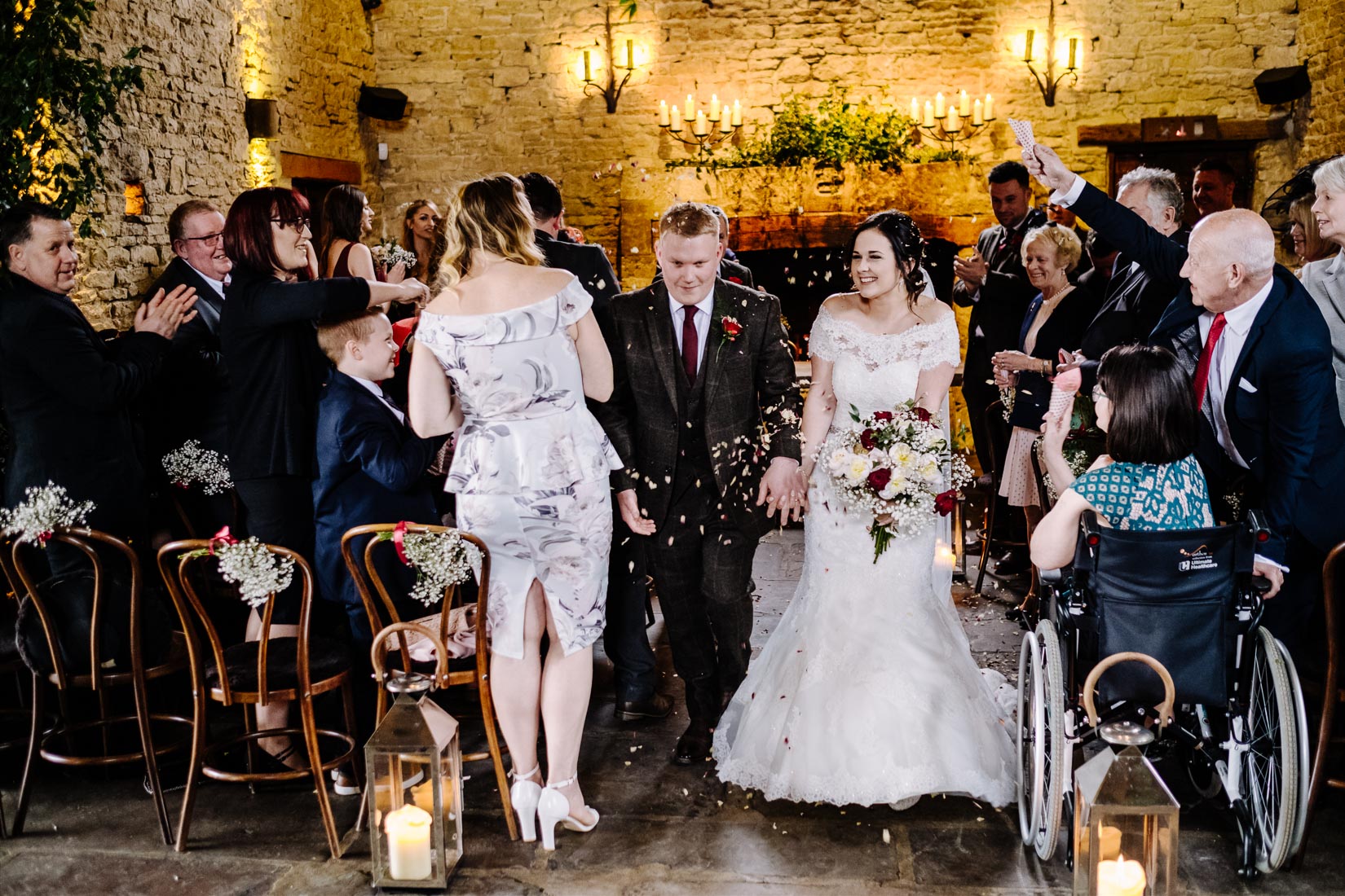 A Bride and Groom covered in confetti leaving their wedding at the Bay Tree, Burford.