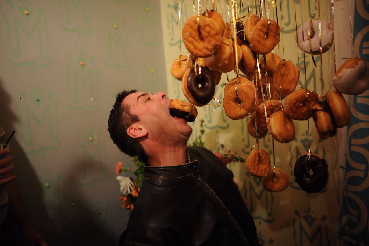 A participant obliges the no-hands rule while navigating a donut chandelier during “WhoDonut: A Cereal Killing.”