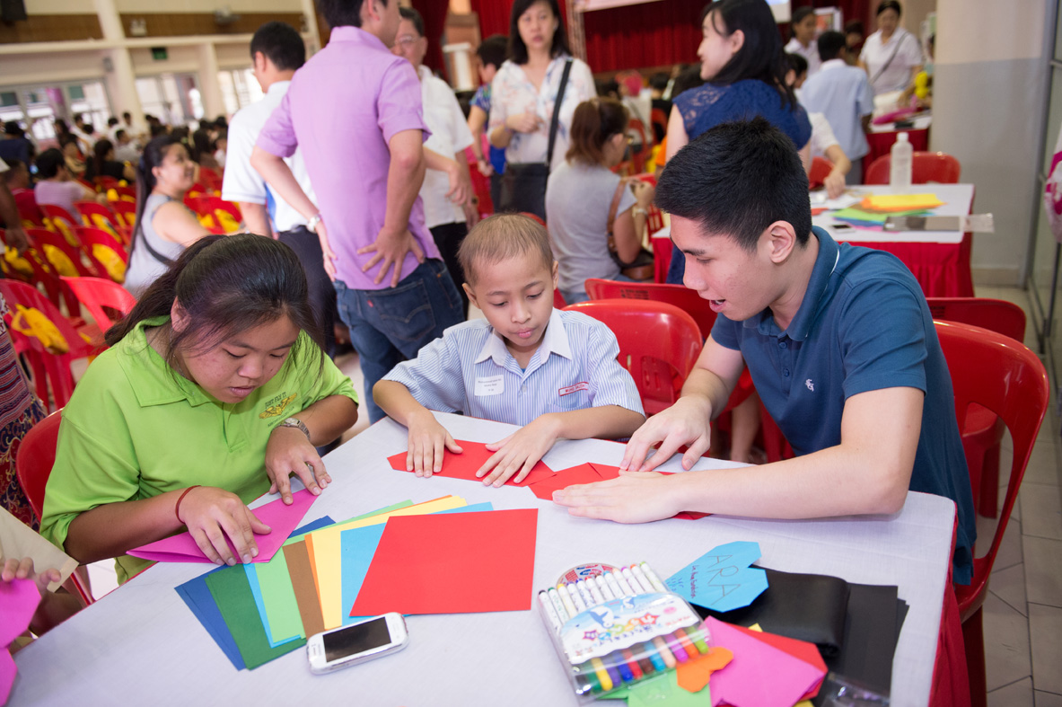  (Above) Joyce (left) and Roy (right) patiently teaching an award winner to fold a heart origami at one of the fringe booths.