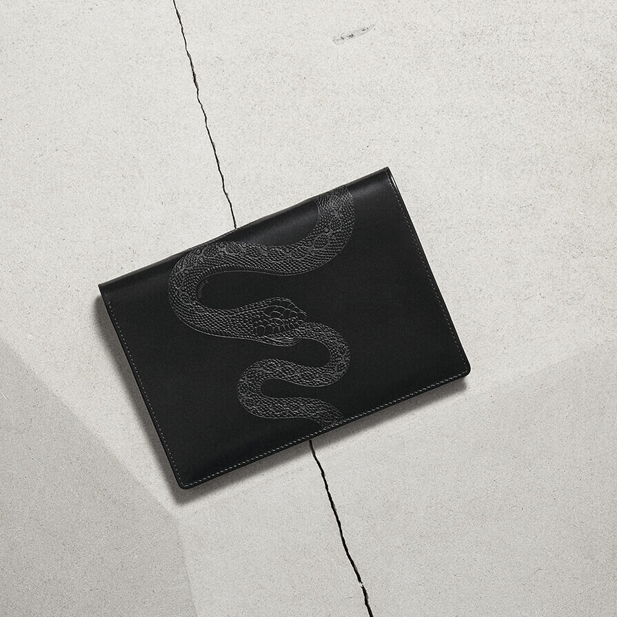 Oliver Ruuger wallet shot from above. Snake etching on leather, sitting on stone.