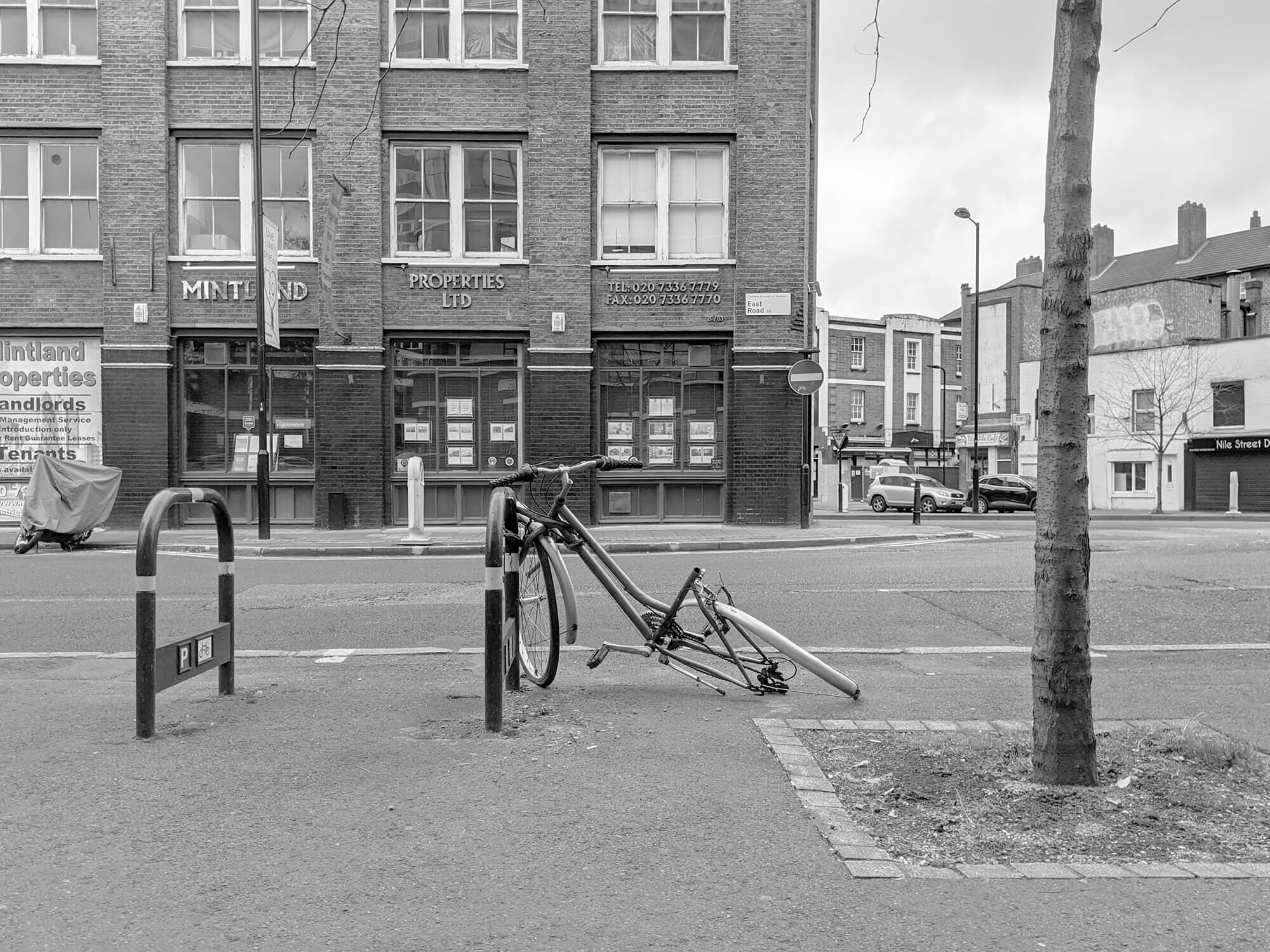 De parted bike frame lying on London street. Black and white.