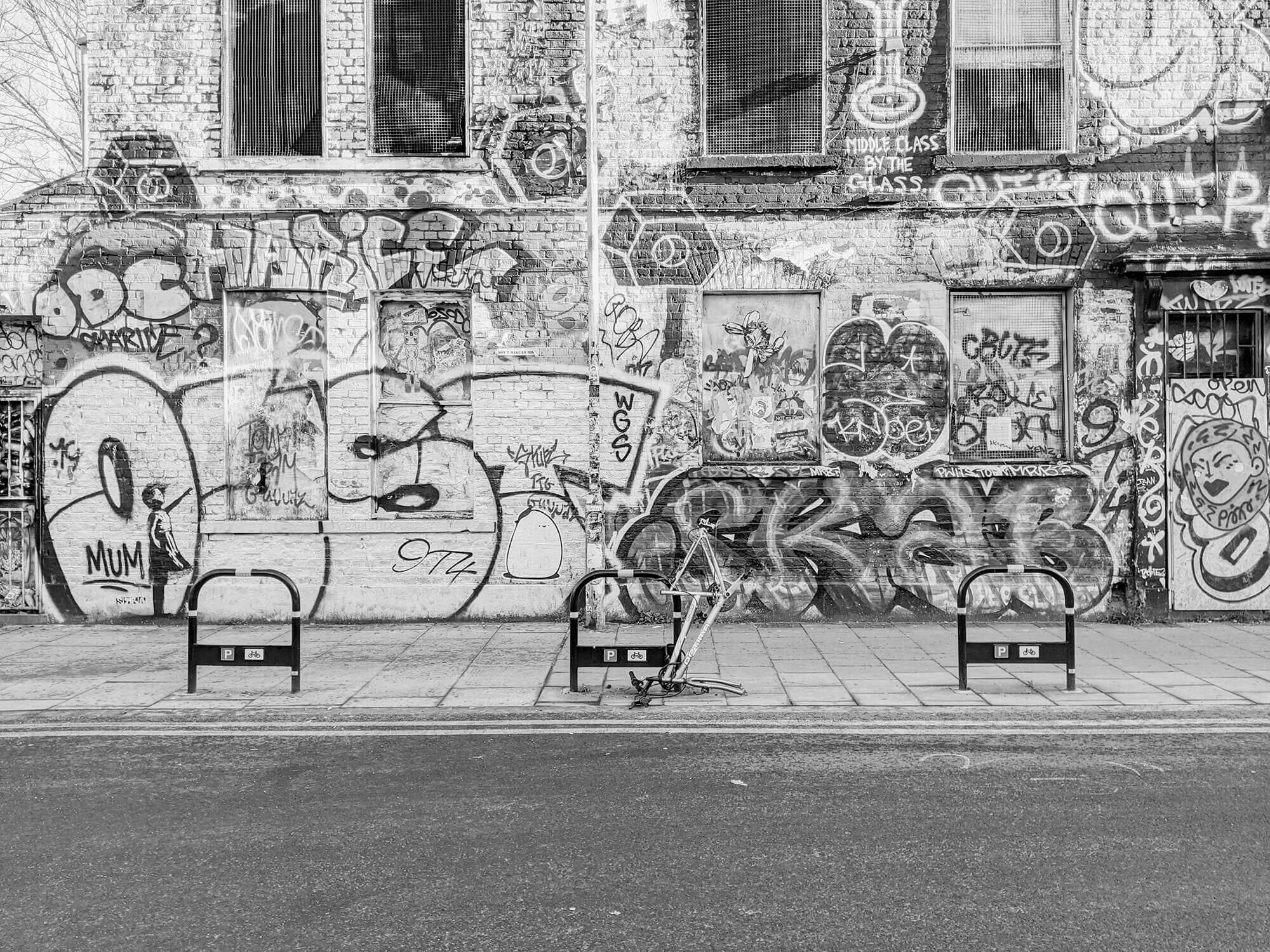 Abandoned building covered in graffiti, with bike chained to stand.