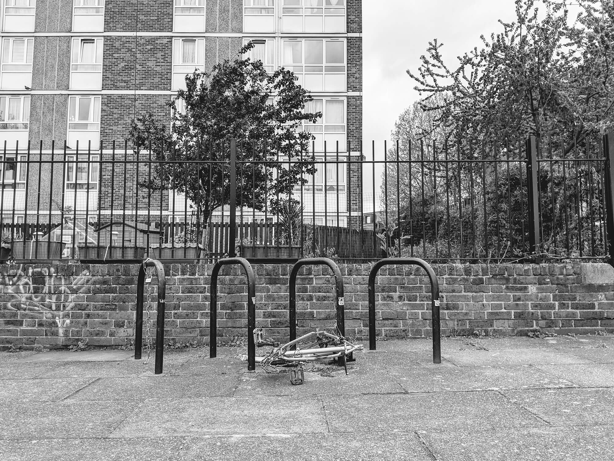 Old bike discarded on London streets. Hi rise flats in the background.