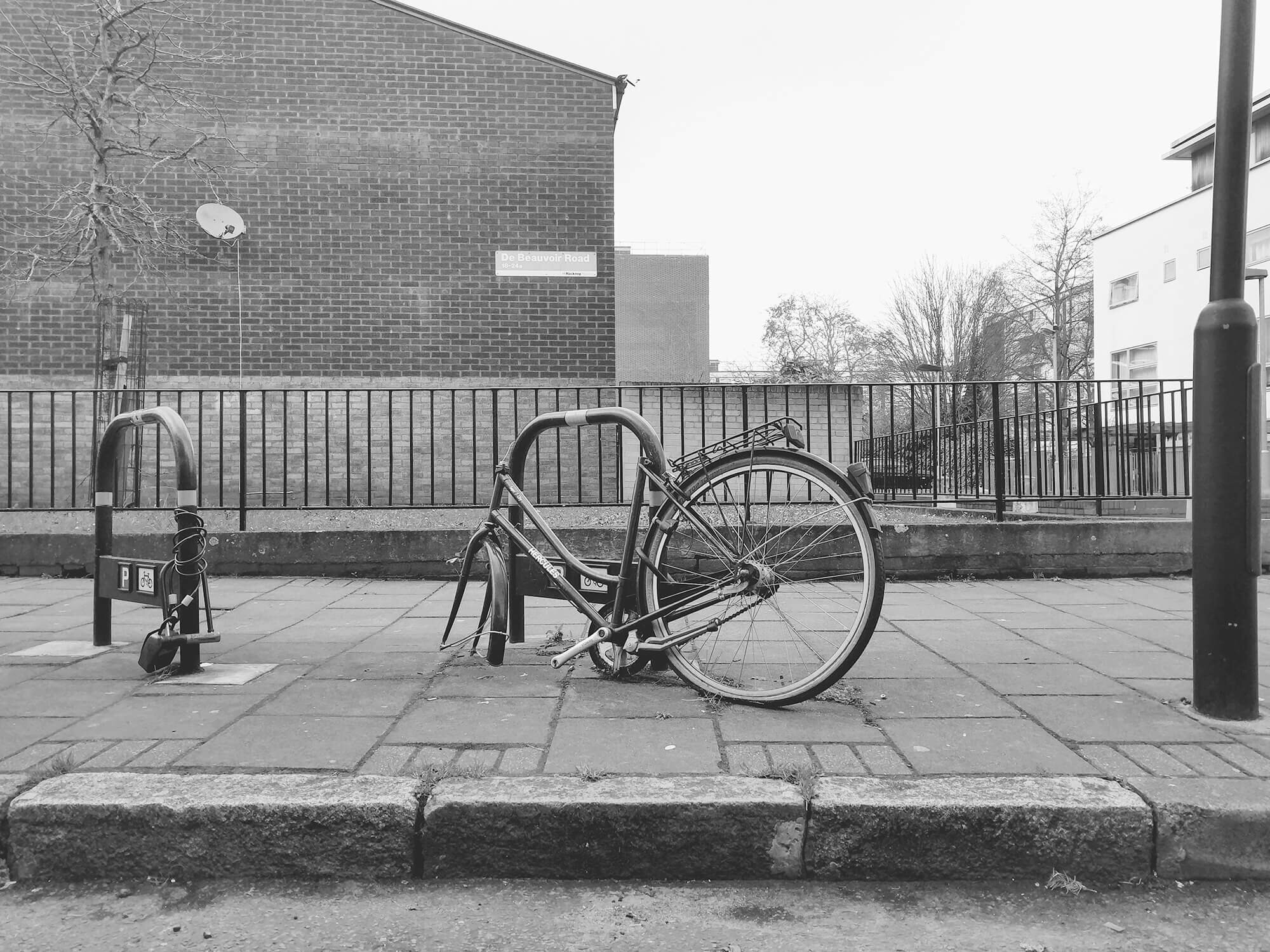 Town bike missing front wheel. abandoned on a London street. Black and white.
