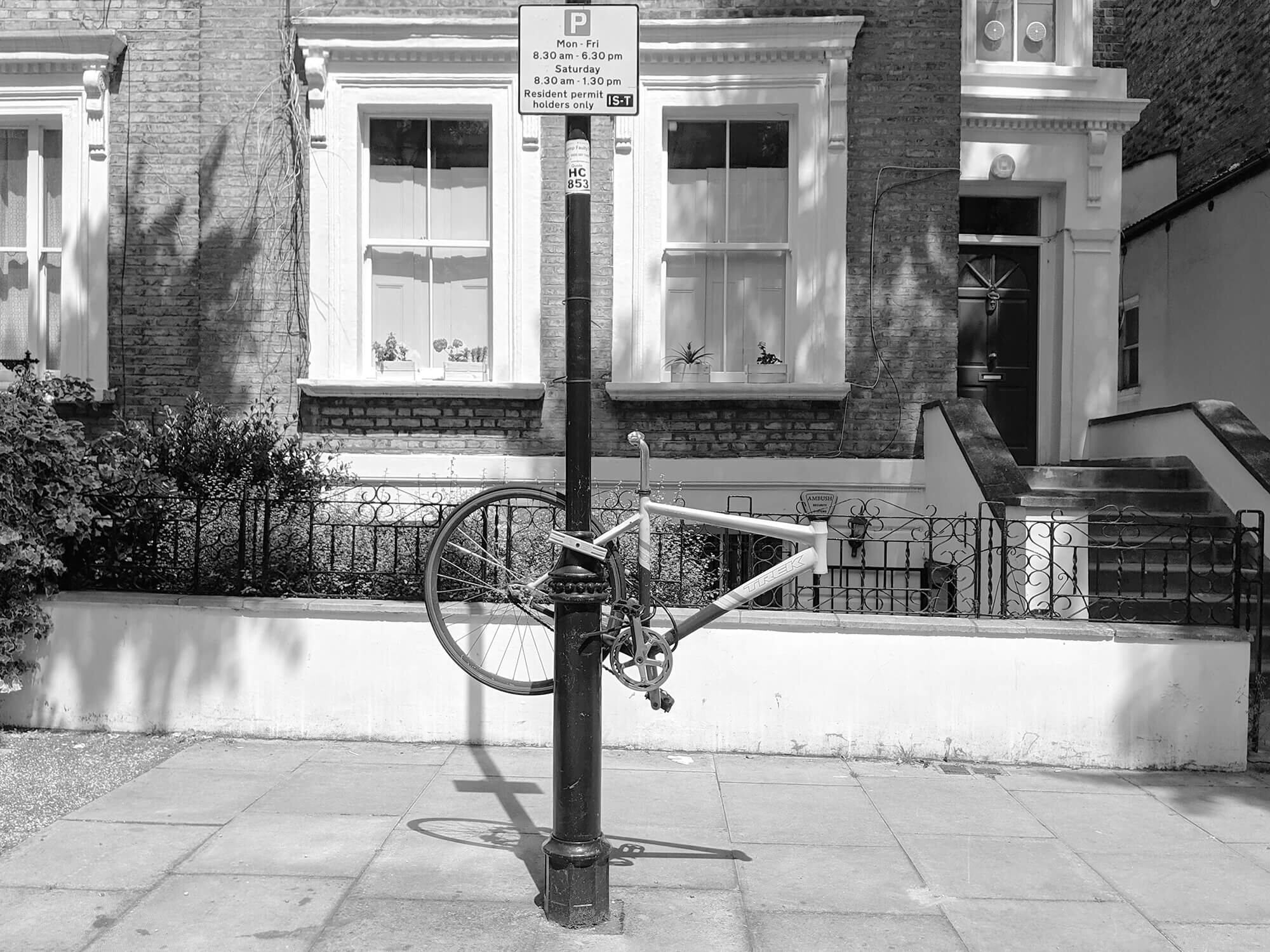 Road bike hanging on a lamppost. No front wheel or forks. London street.