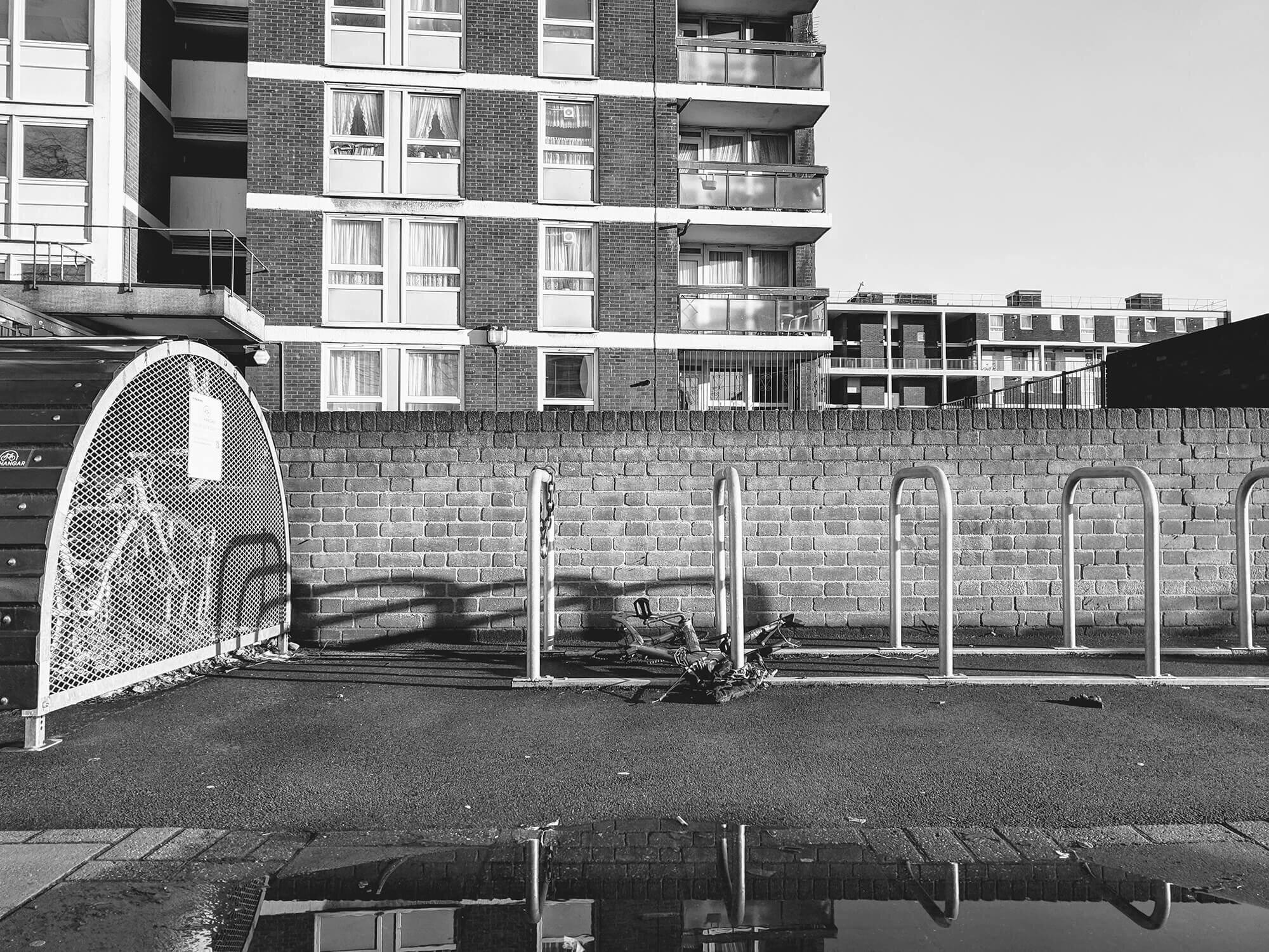 De parted mountain bike lying on the floor in front of hi rise flats.