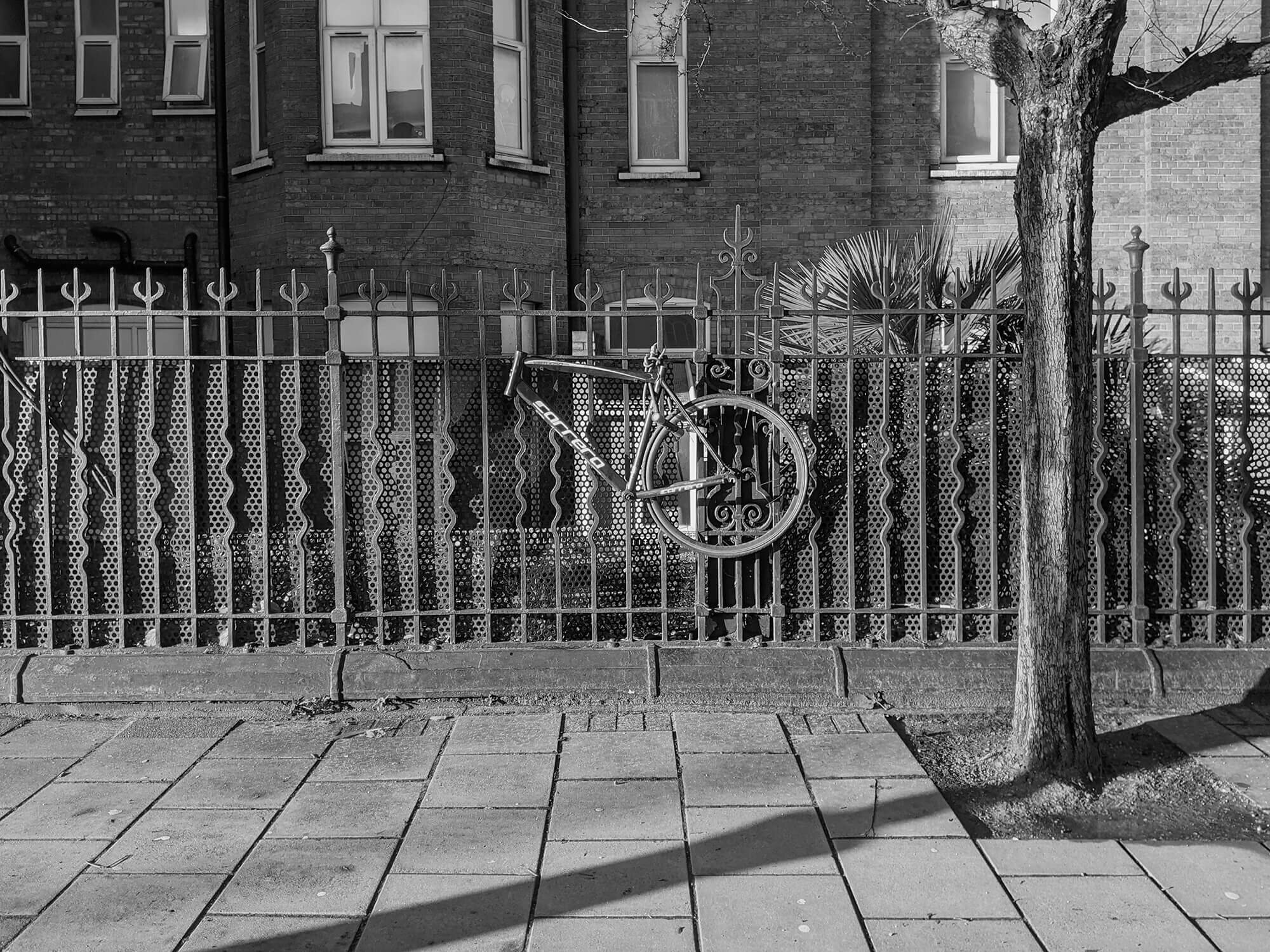 bike hanging on railings. front wheel missing.