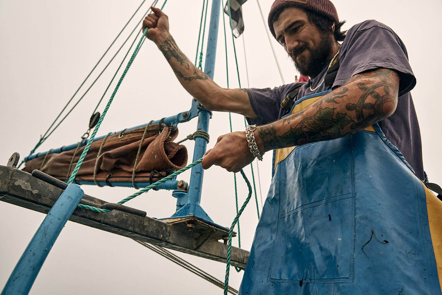 Fisherman pulling ropes on boat, wearing silver bracelet