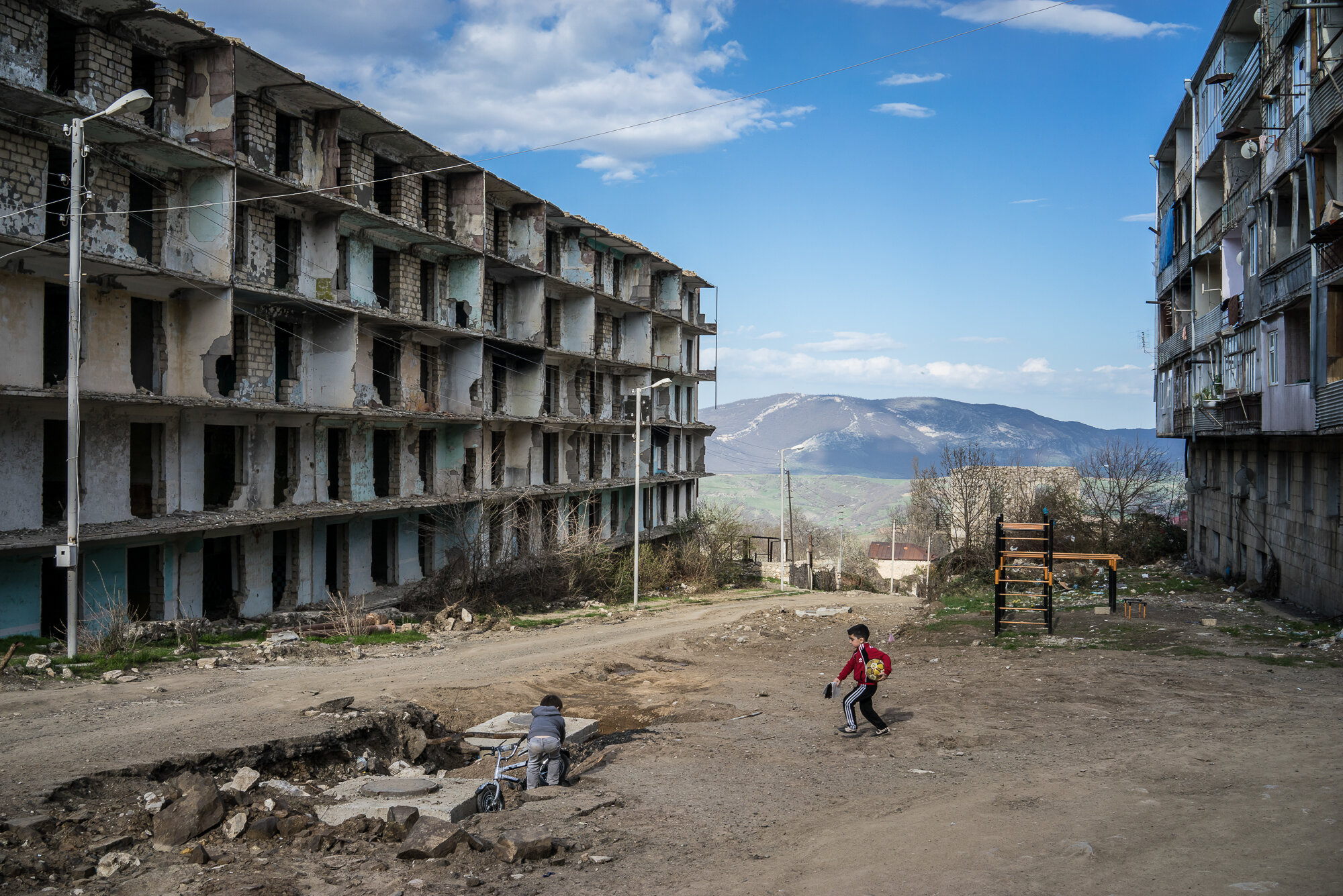  Boys play on a street next to a building destroyed by war more than twenty years earlier. Shushi, Nagorno-Karabakh. 2015. 