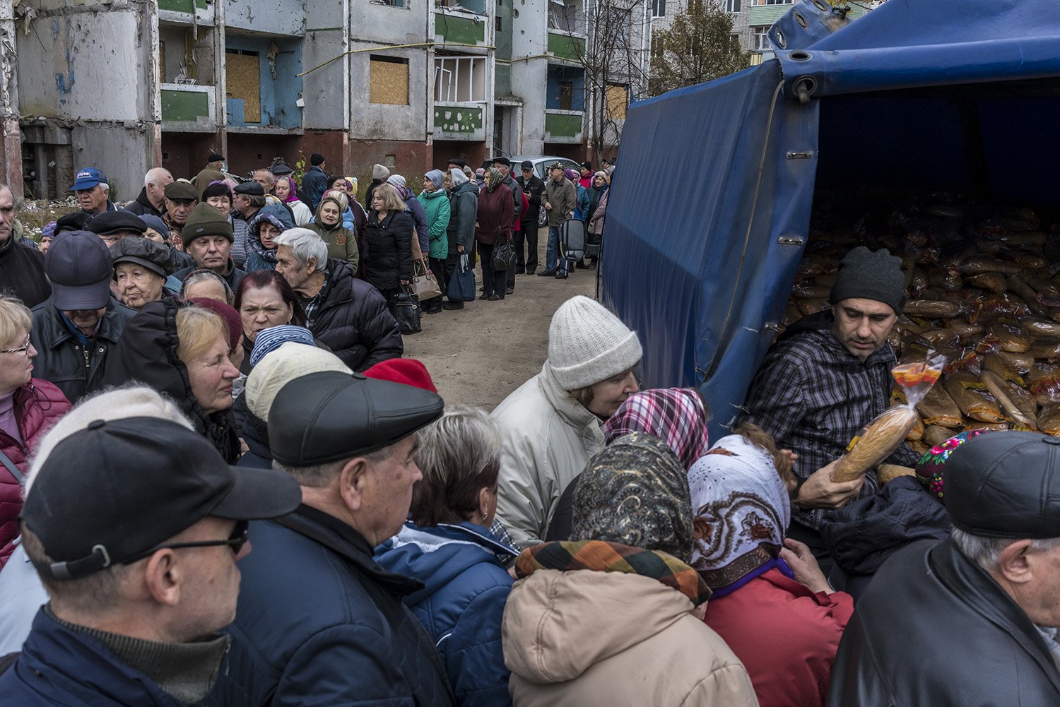  Local residents wait in line to receive free loaves of bread next to high rise residential buildings that were heavily damaged during airstrikes in March on Wednesday, October 19, 2022 in Chernihiv, Ukraine. 