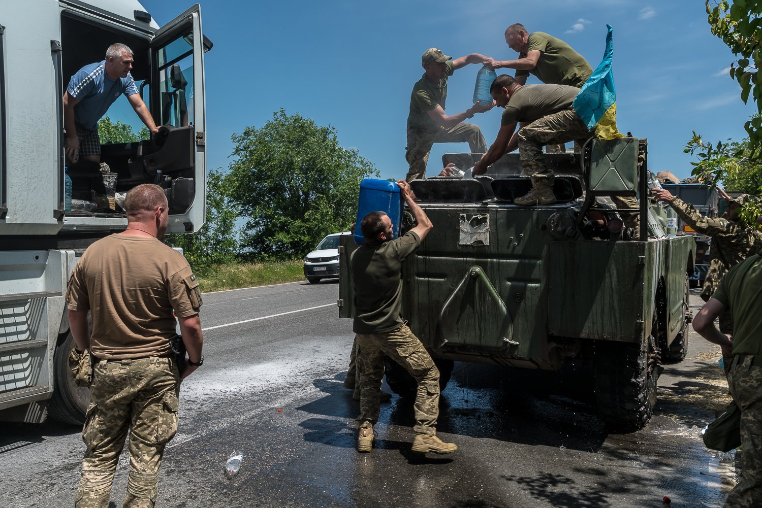  Ukrainian military servicemembers get water from a passing truck driver after their BTR caught fire while driving on Friday, June 9, 2023 in Nechayane, Ukraine. 