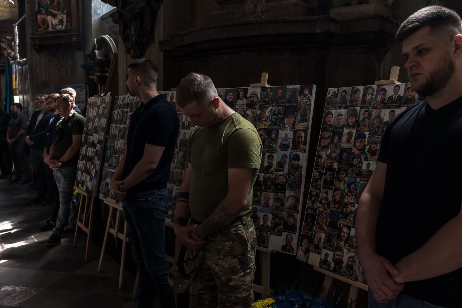  Mourners stand in front of photographs of Ukrainian soldiers killed during Russia's invasion of Ukraine during the funeral for Bohdan Didukh and Oleh Didukh, both Ukrainian soldiers who share a last name but are unrelated, at Sts. Peter and Paul Gar