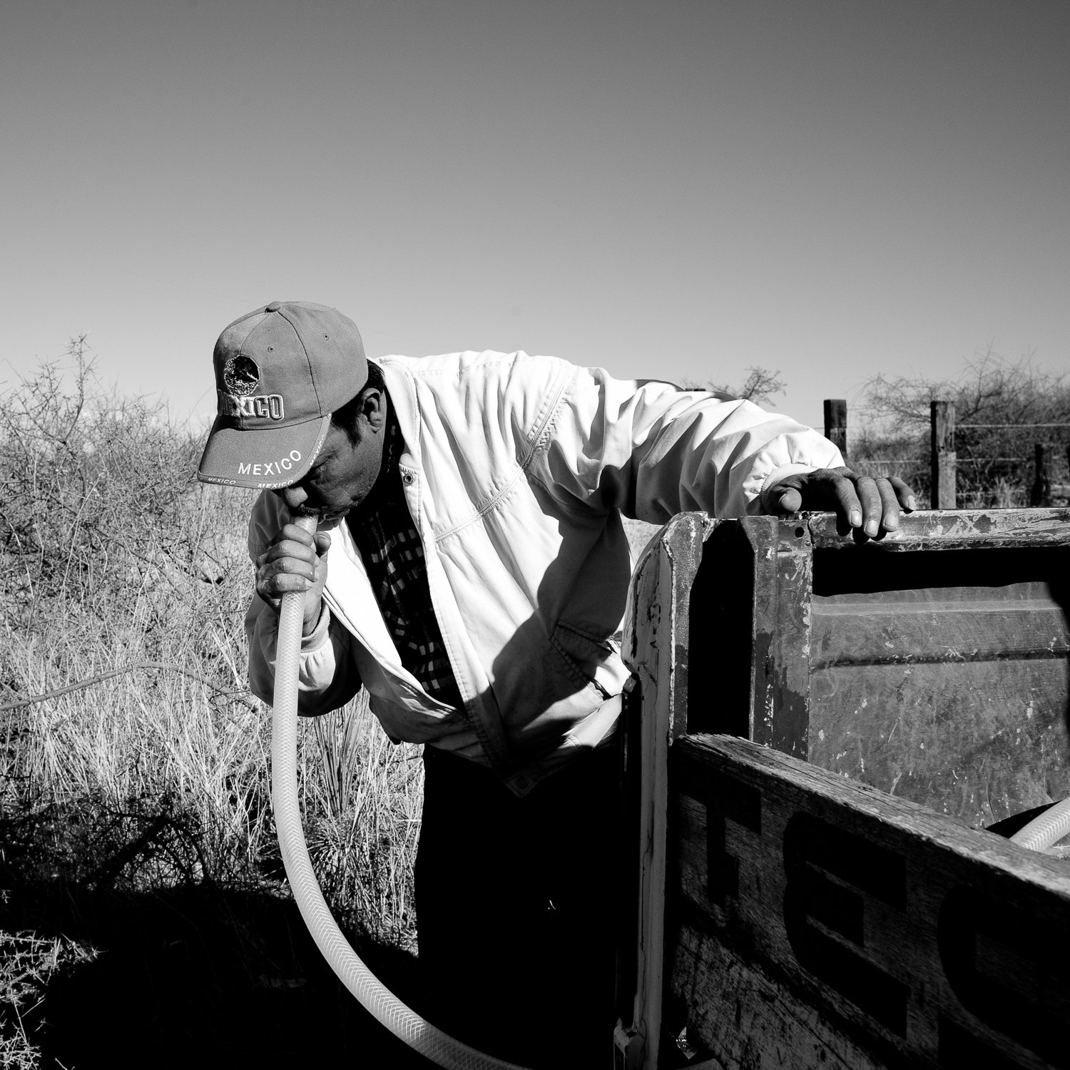  Fernando Lerma, a volunteer with the Migrant Resource Center, siphons water through a hose while filling water tanks for thirsty migrants in the desert near Naco, Sonora, Mexico. 