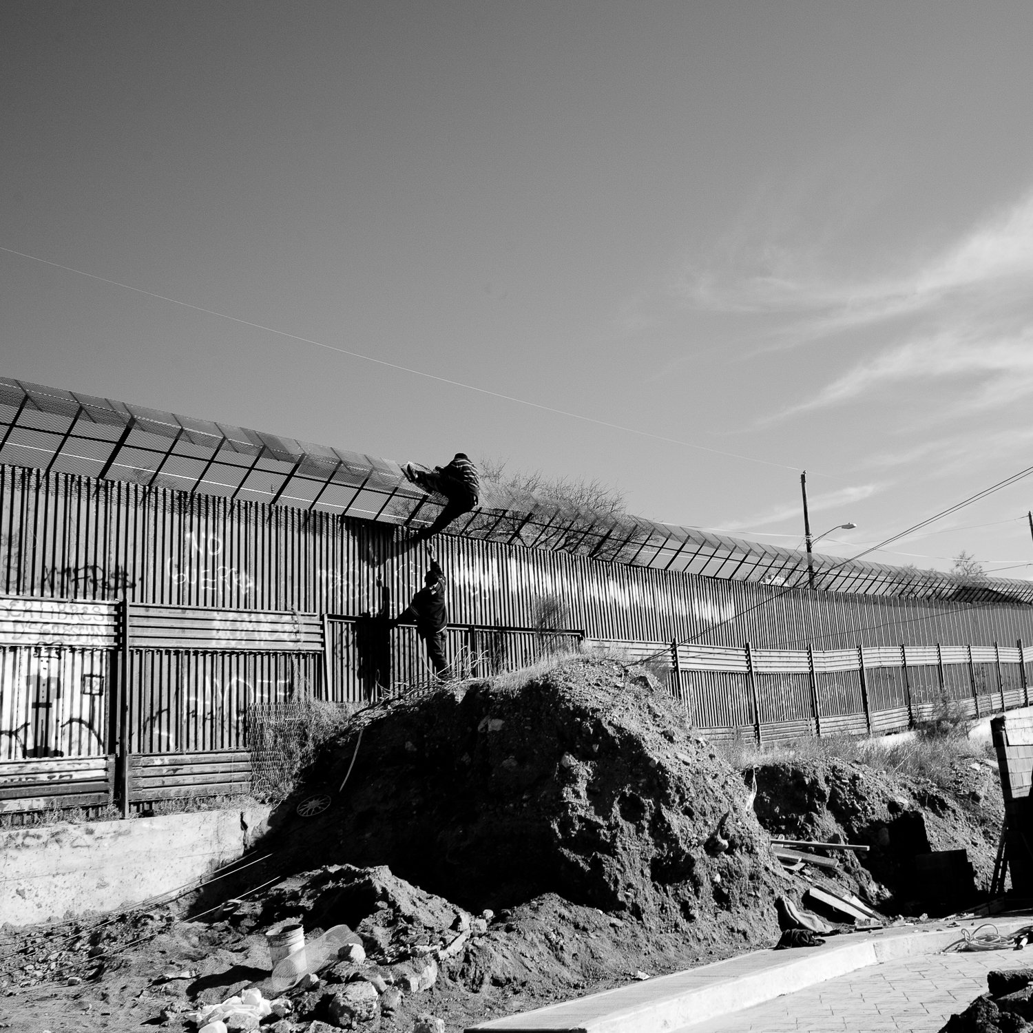  Two men climb over the fence separating the United States and Mexico in an attempt to cross into the United States illegally from Nogales, Sonora, Mexico. 