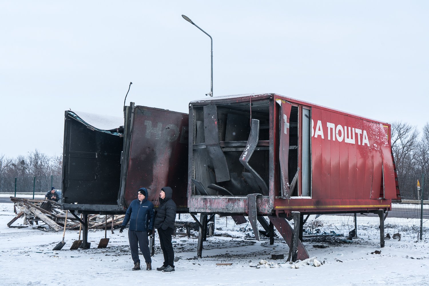  Men stand next to destroyed trailers at a Nova Poshta distribution warehouse that was struck by two Russian missiles and four Russian attack drones the previous day on Wednesday, January 14, 2026 in Novyi Korotych, Ukraine. It was the fourth separat
