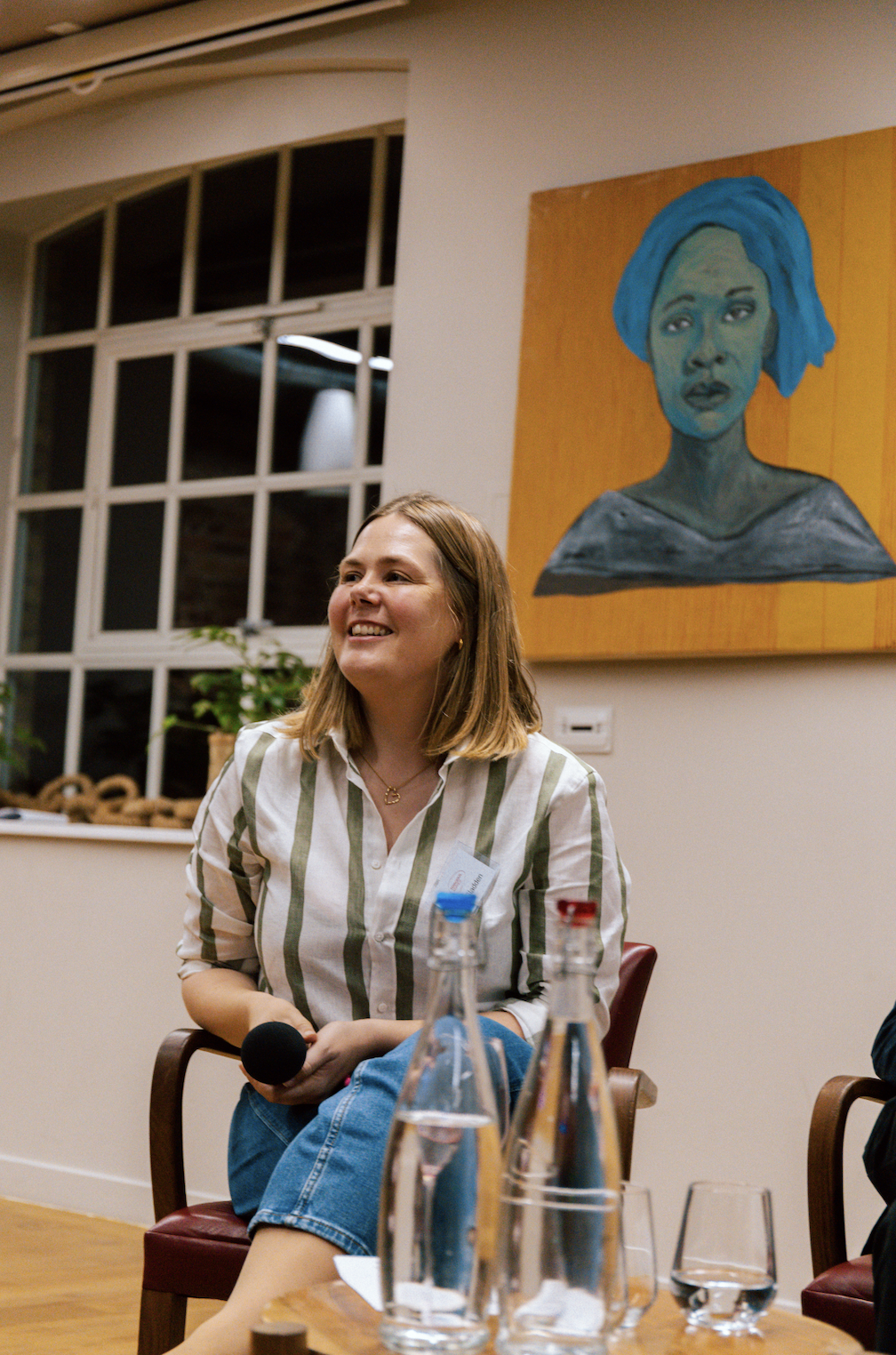 Katherine Sladden, smiling, holding microphone and chairing a panel