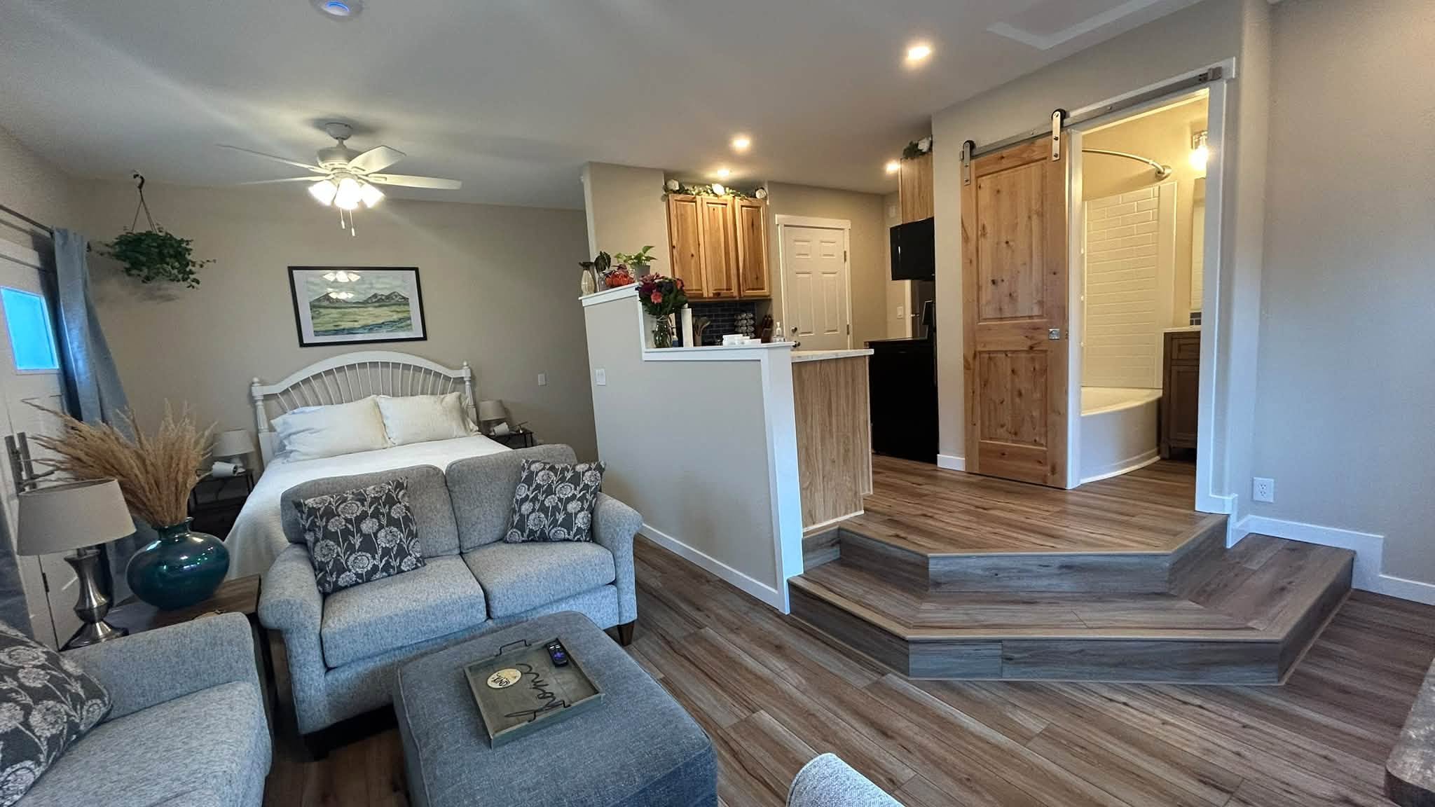 Garage converted into a furnished living space with a kitchen, bathroom and sliding barn door.