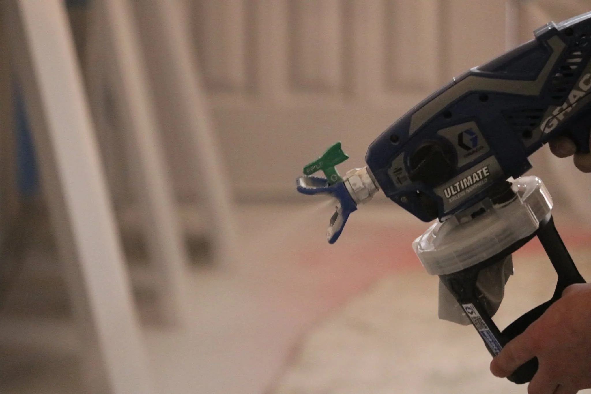 Handheld paint sprayer during interior painting work.