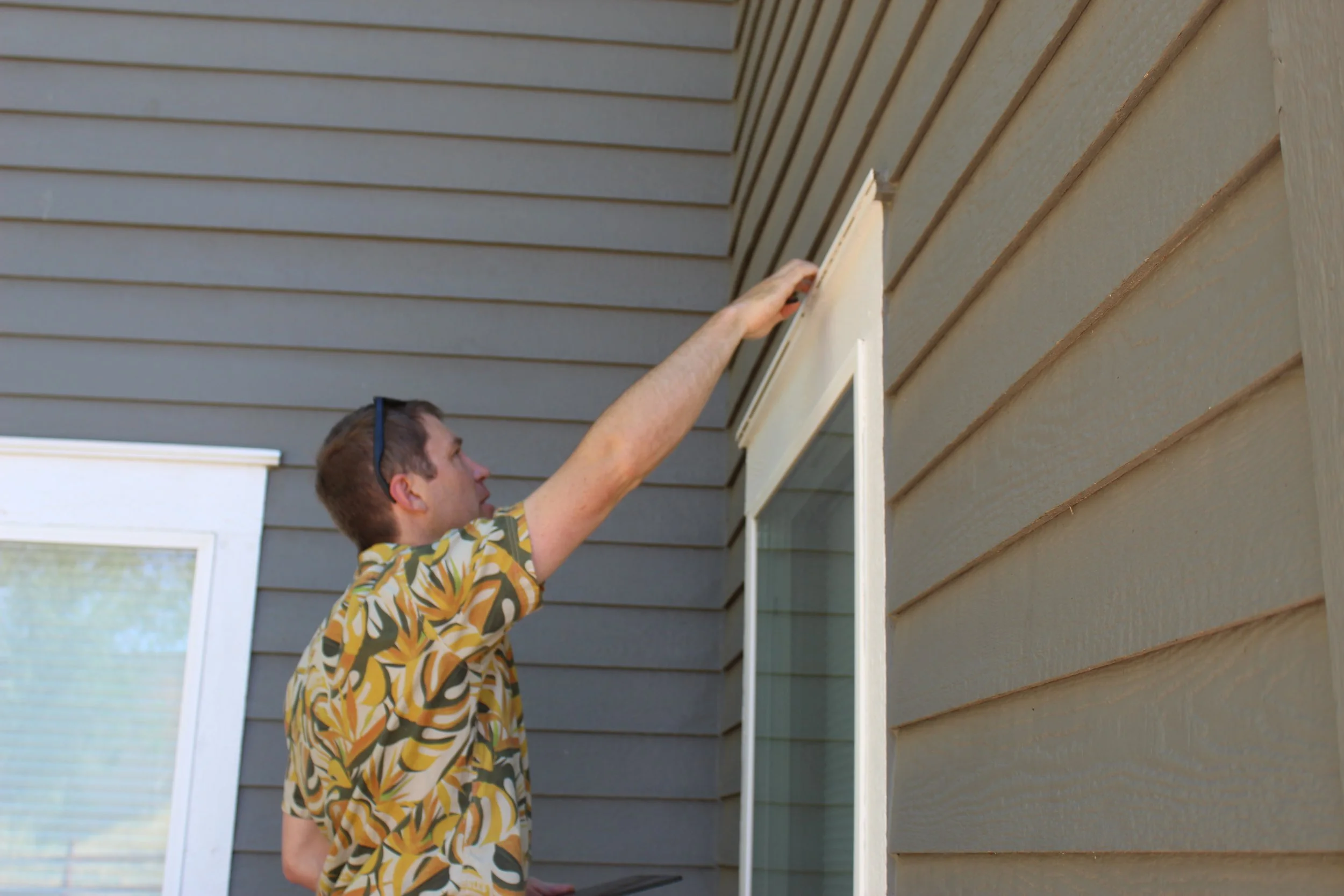  Sam Feuerborn inspecting siding and window trim for wildfire vulnerability. 
