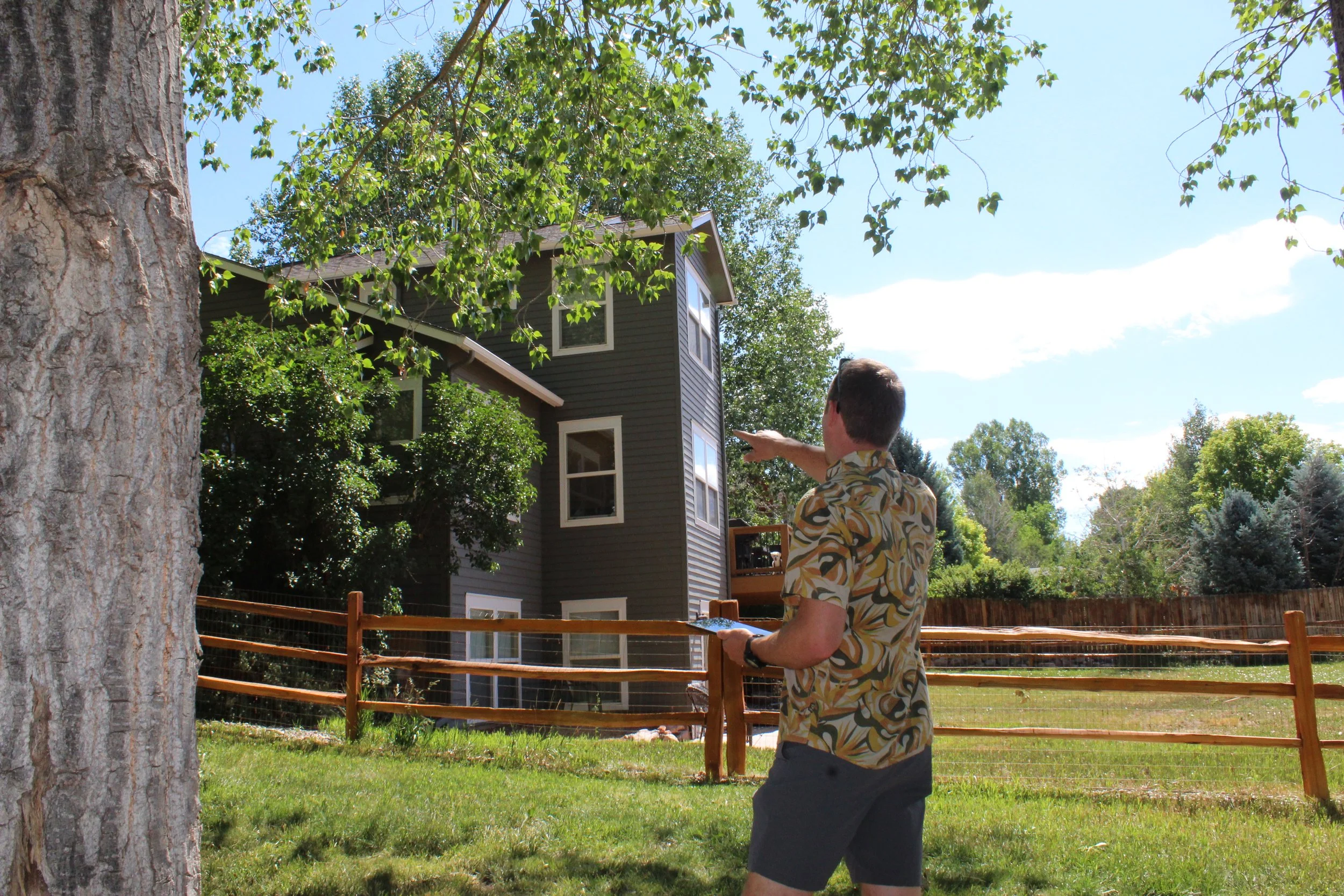  Sam Feuerborn assessing overhanging tree limbs and upper-level siding near the home. 