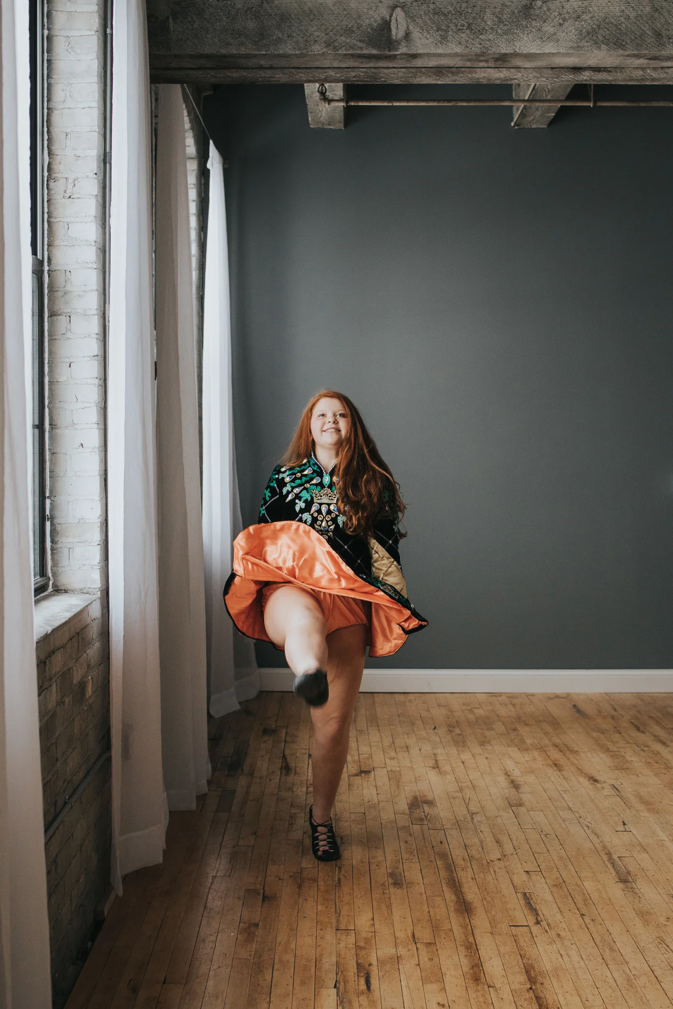 Irish dancer kicking with orange skirt - Lifestyle Family Photography Twin Cities
