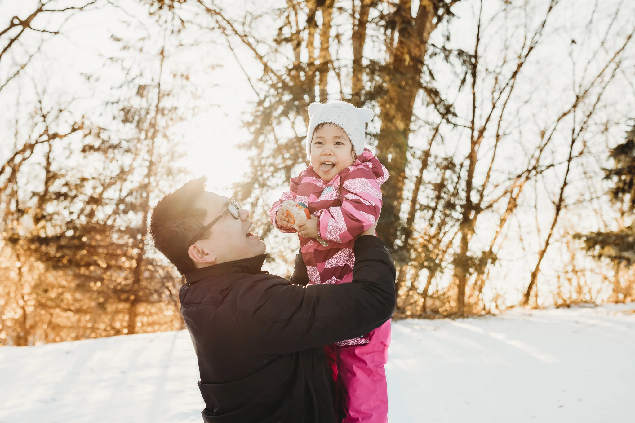 daddy holding baby girl up in the sky during winter - Minnesota family photographer