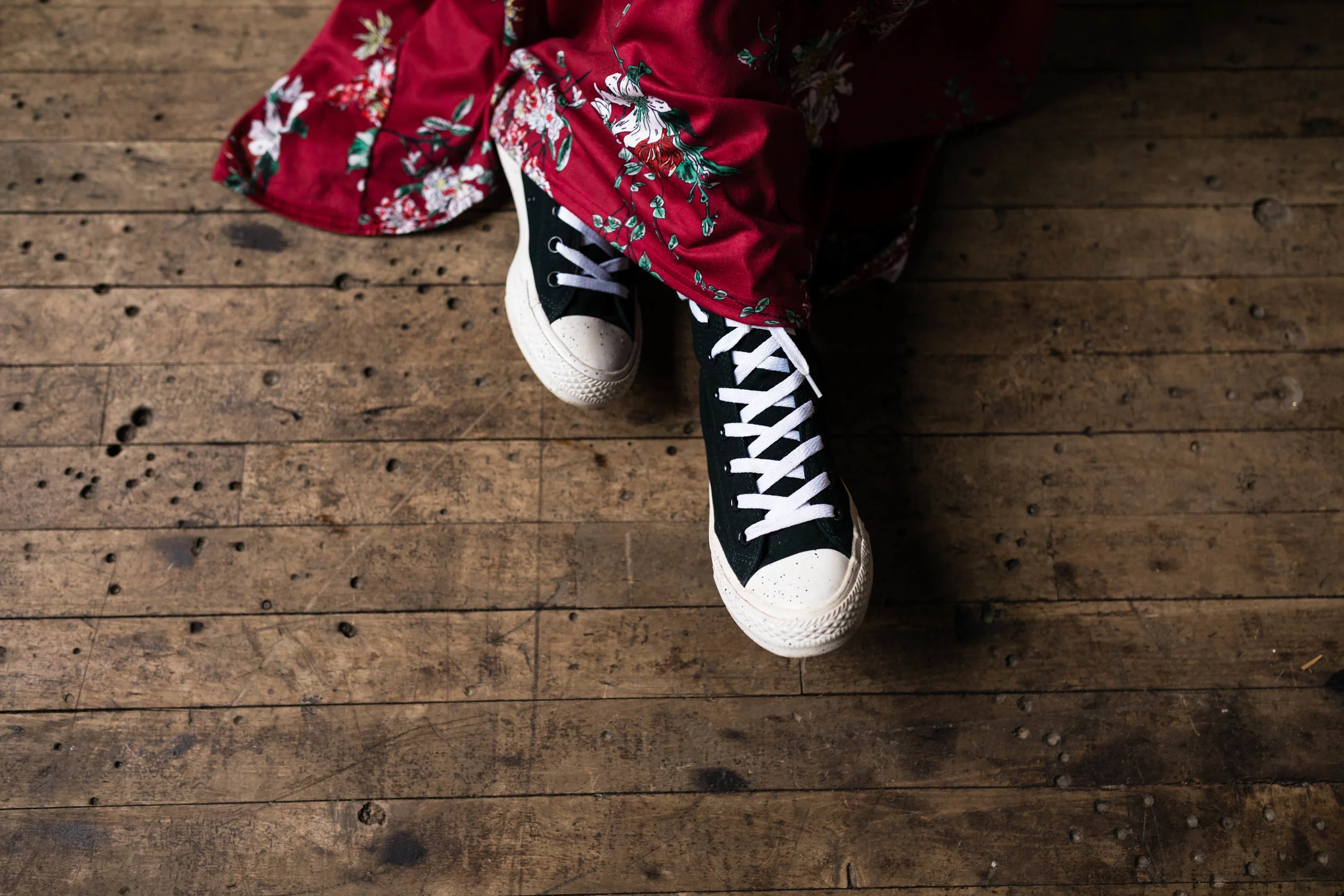 girl wearing black converse shoes with a red flowered dress