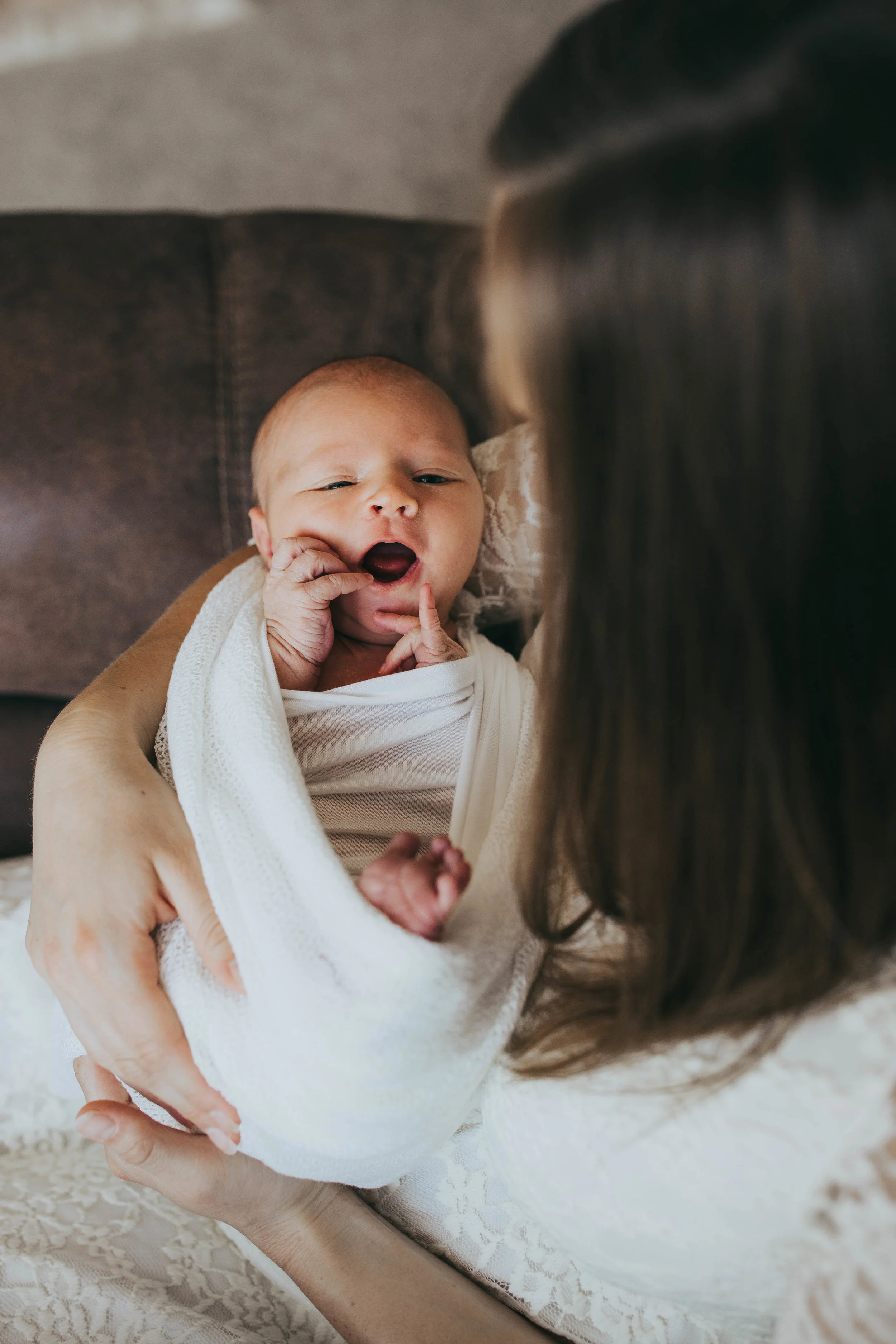 newborn baby held by mother yawning - AMG Photography