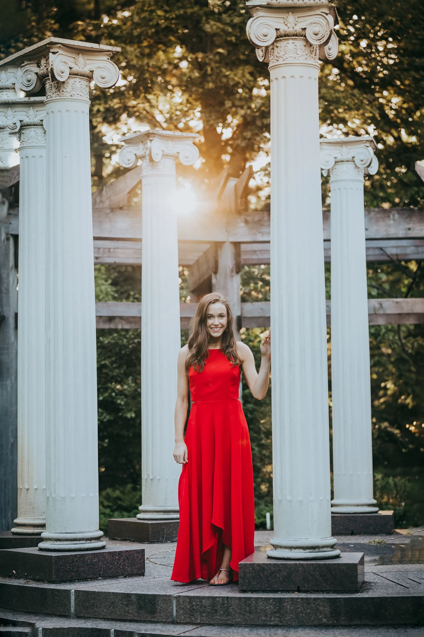 girl in red dress standing by Greek Pillars in the sunset - Wayzata High School Photographer