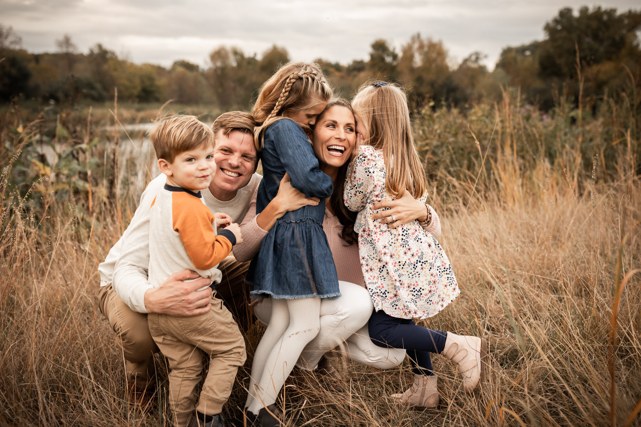 mom and dad playing with their three children in a field | AMG Photography