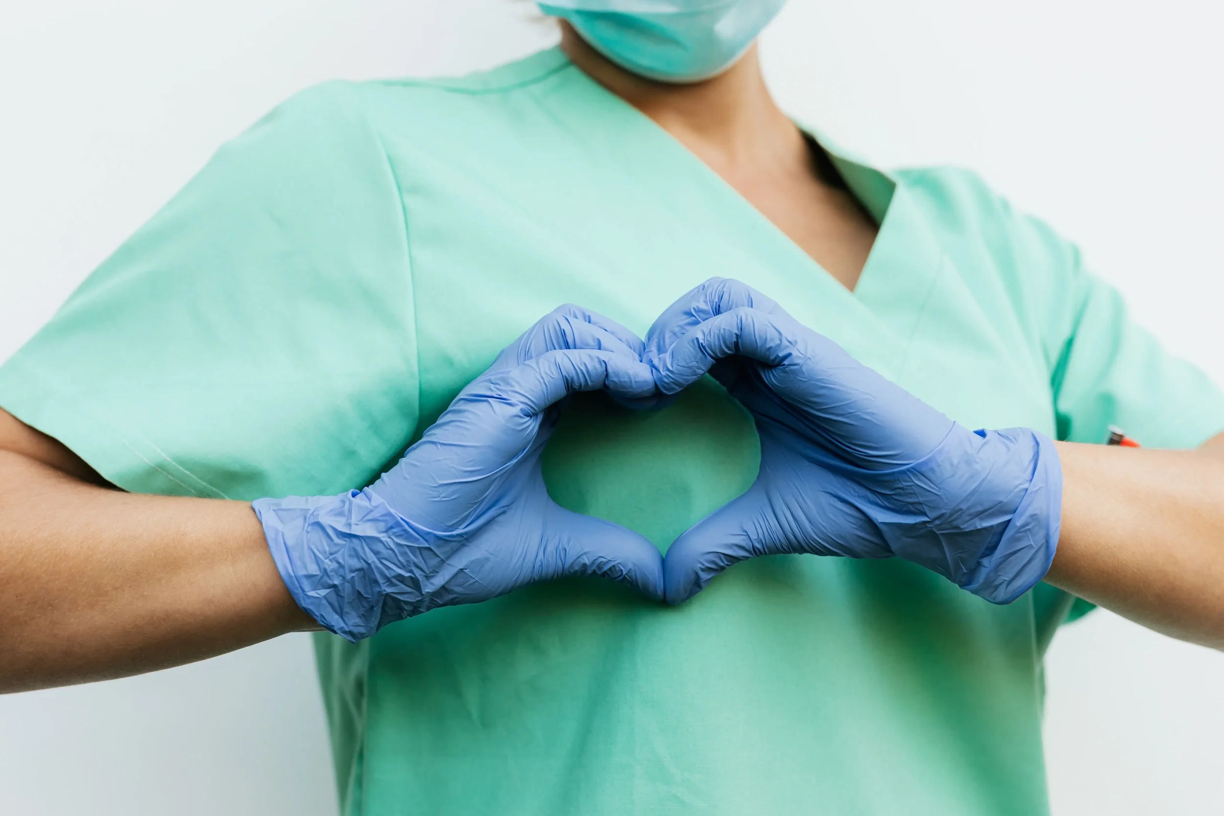 healthcare worker with gloved hands making a heart