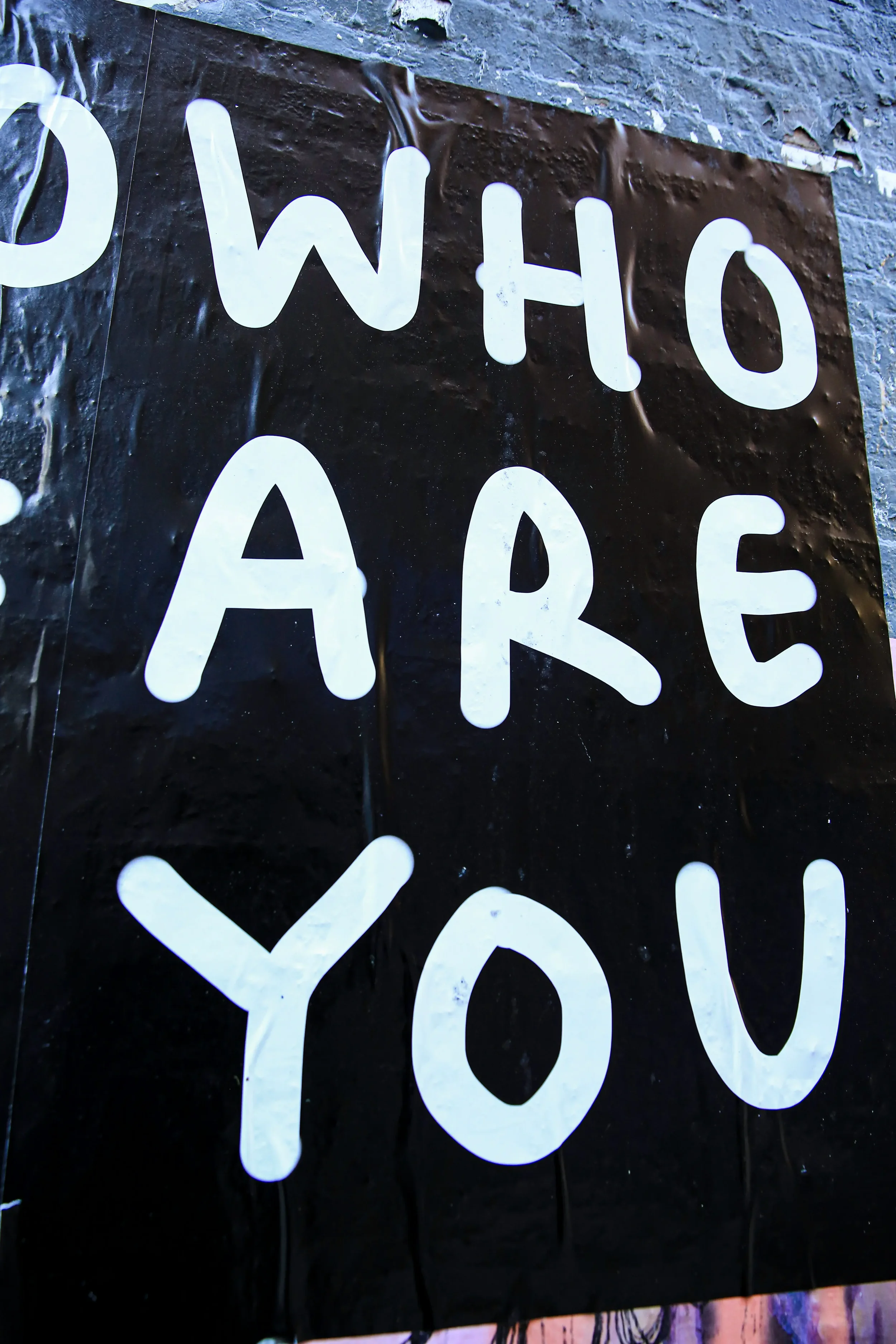 A sign on a building that reads: Who are you?