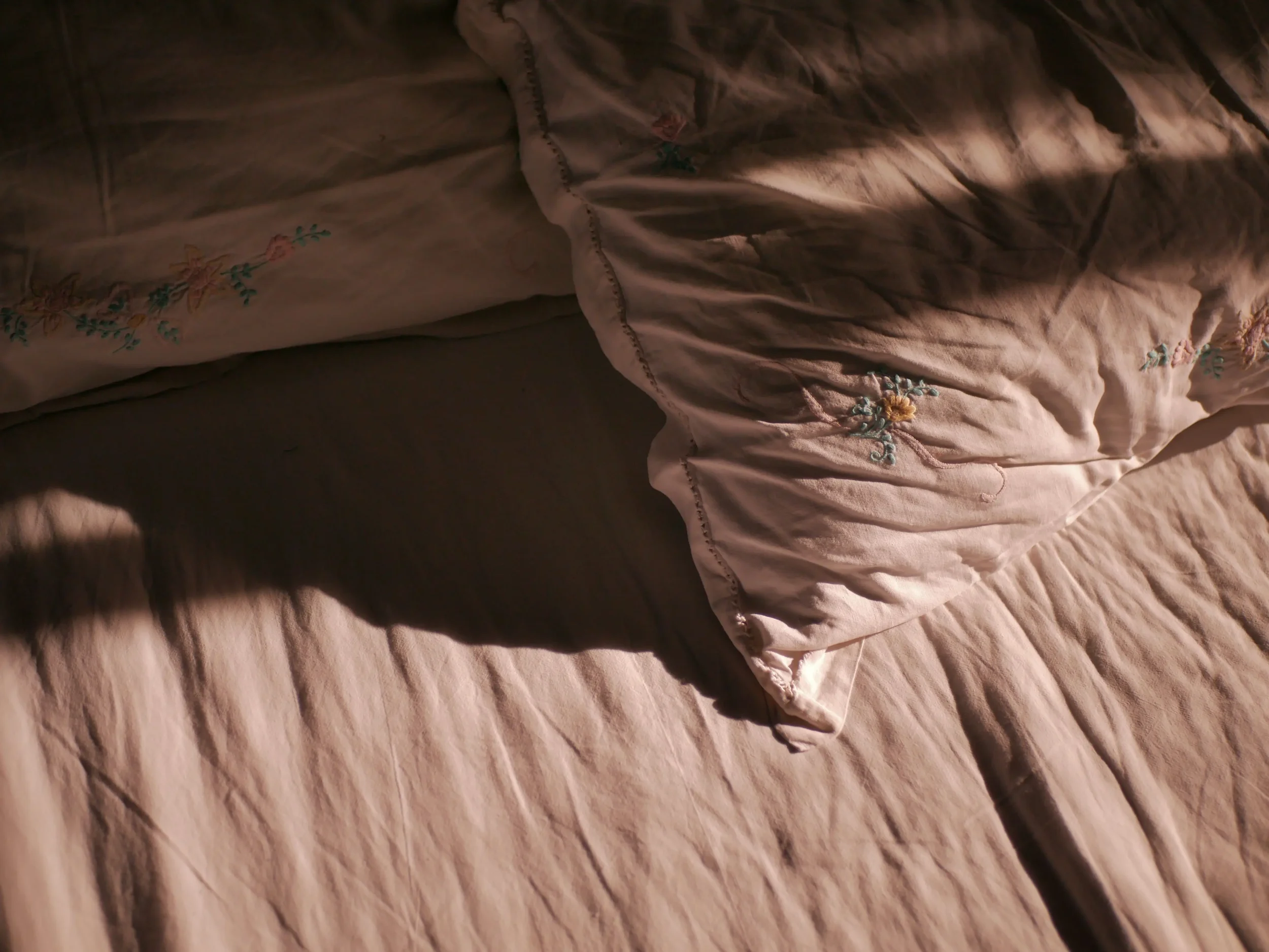 An empty unmade bed with brown sheets