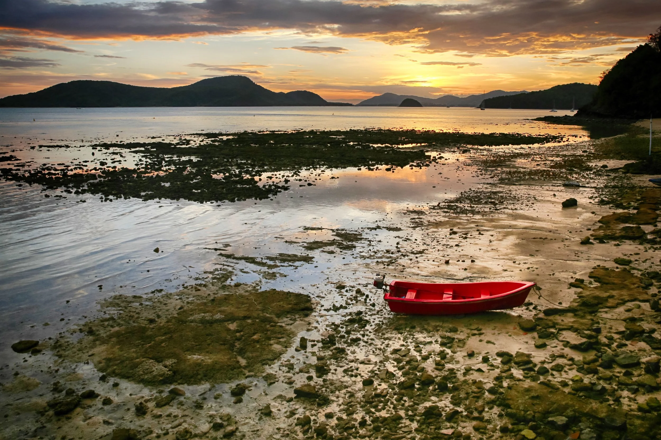 A red Thai boat on the shore of Phuket