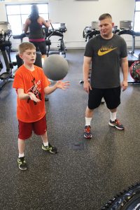 Kenny Schmidt, with his father Ken, works out with the medicine ball.