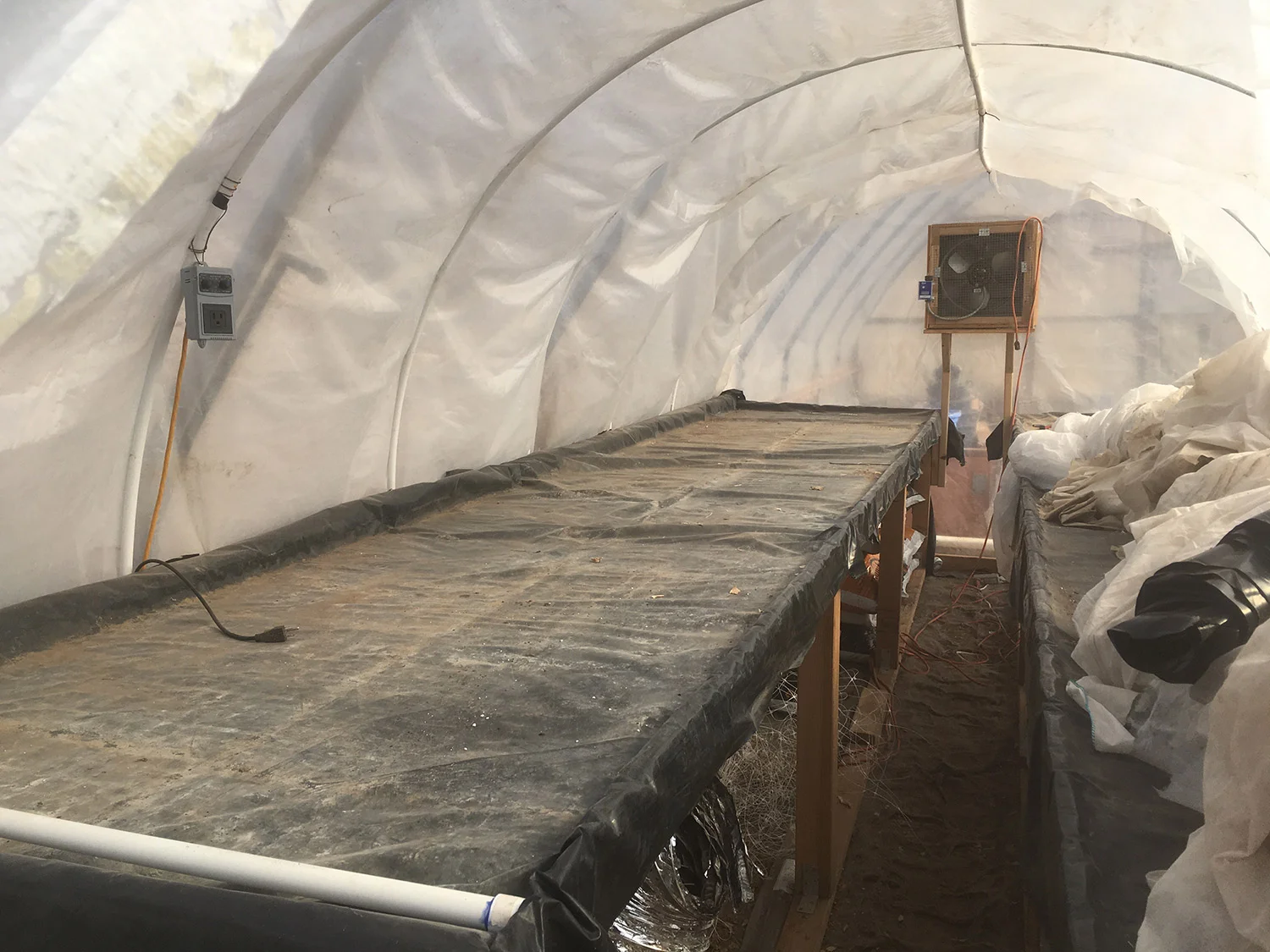 That little white PVC pipe in the foreground is where the water can flood out. There is a bench on the other side too - it's just covered by frost cloth. Storage solutions...