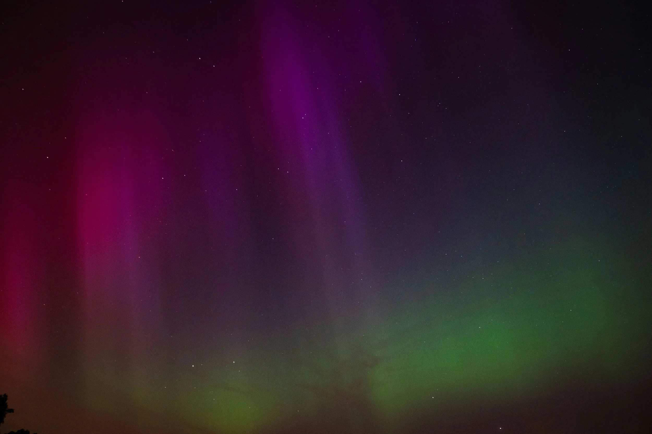 Night sky with green and purple aurora borealis and visible stars.