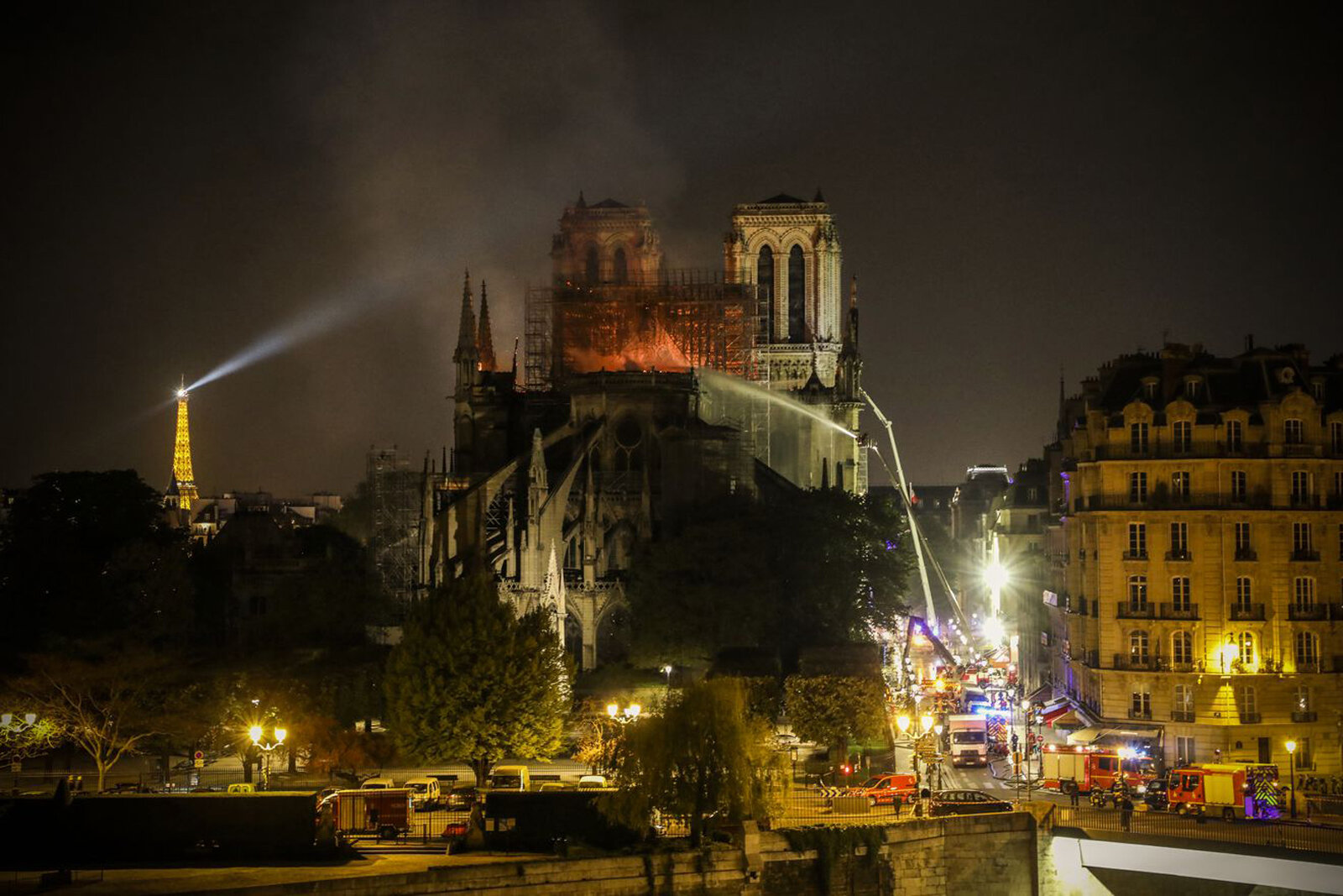  A light atop the Eiffel Tower pierces the smoke billowing from the top of the cathedral as firefighters struggle to contain the fire. Ludovic Marin/AFP/Getty Images 