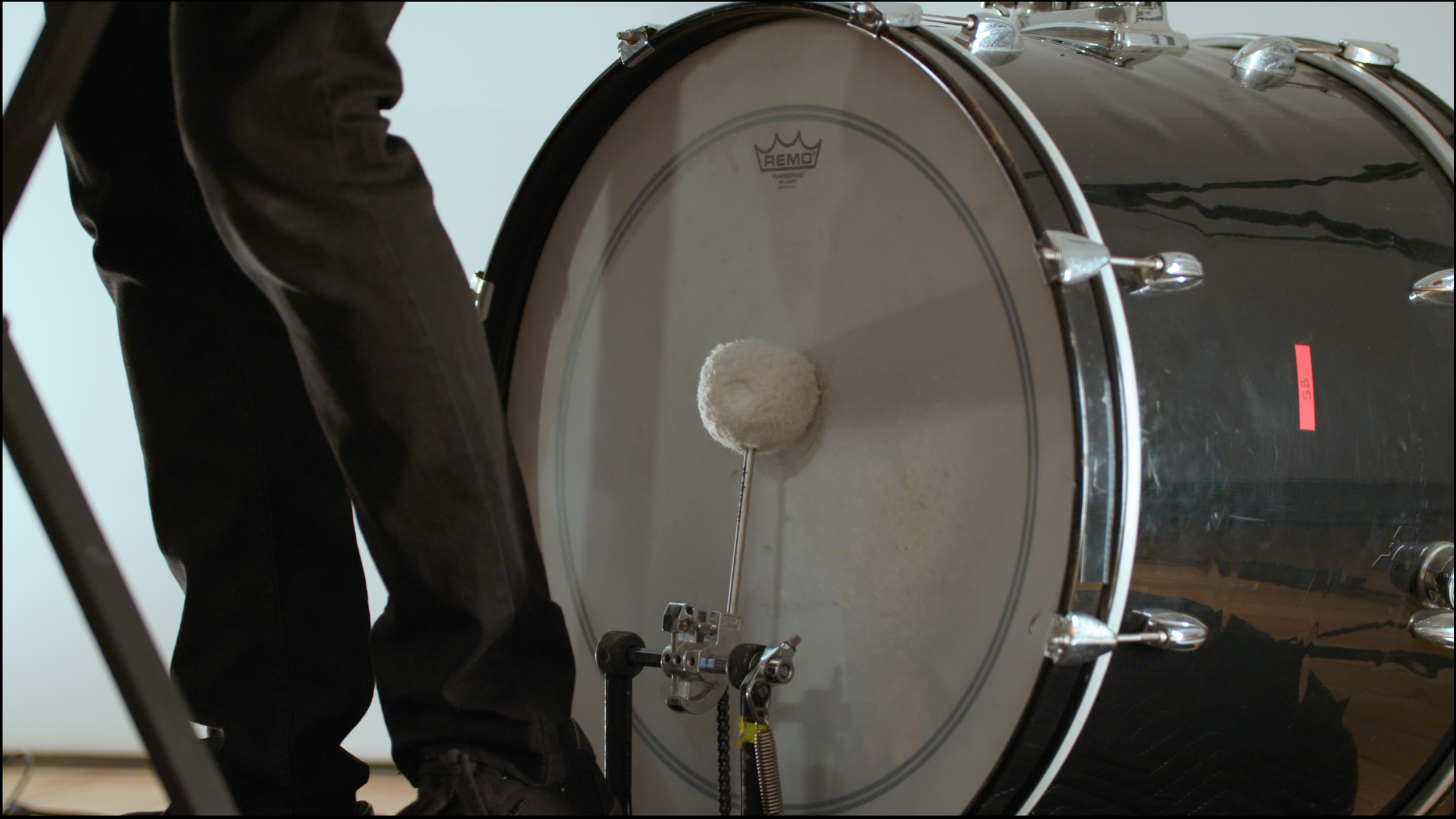 3. A close-up image of a percussionist playing a kick drum behind them with their foot.