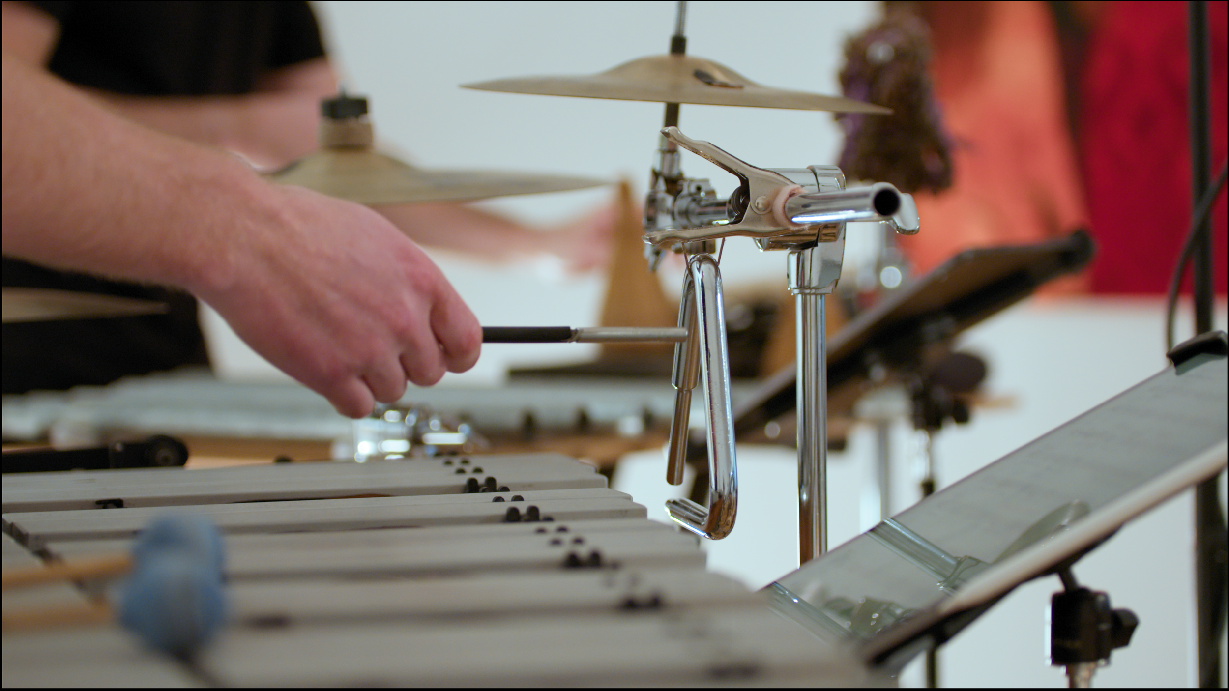 6. A close-up image of a percussionist playing a silver metal triangle with a metal triangle beater.