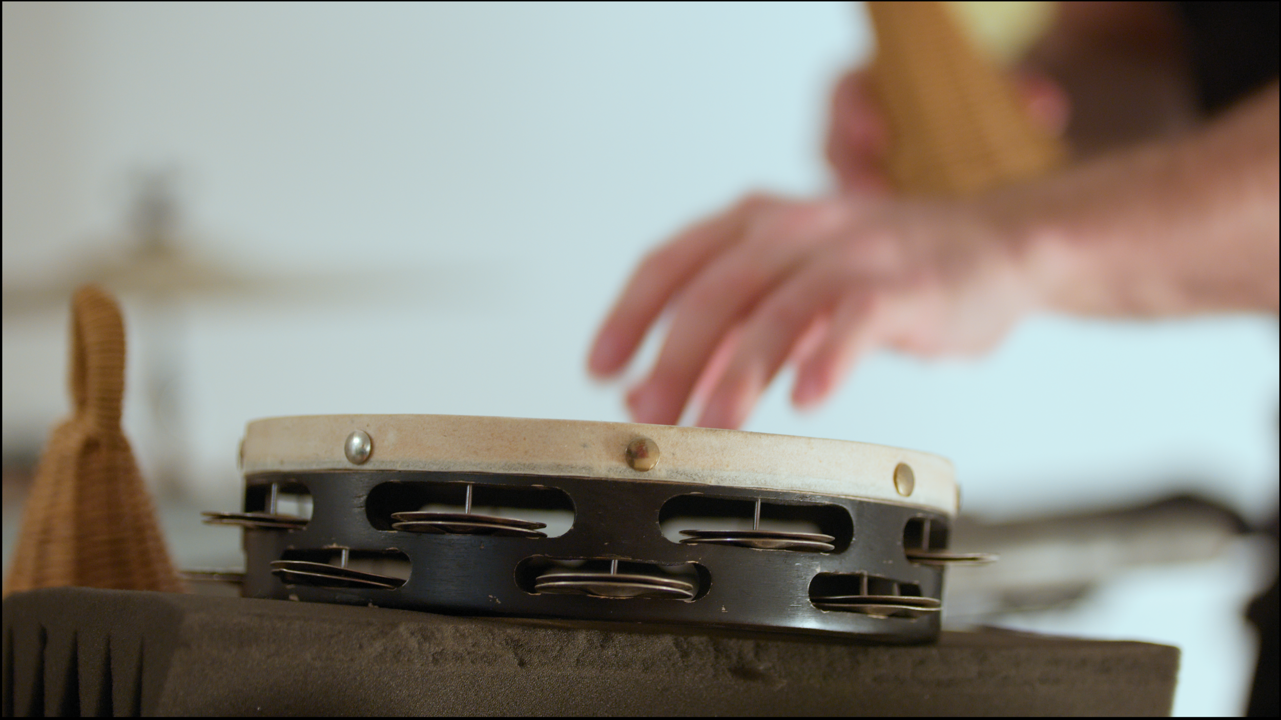 7. A close-up image of a percussionist playing a mounted tambourine with their hands.