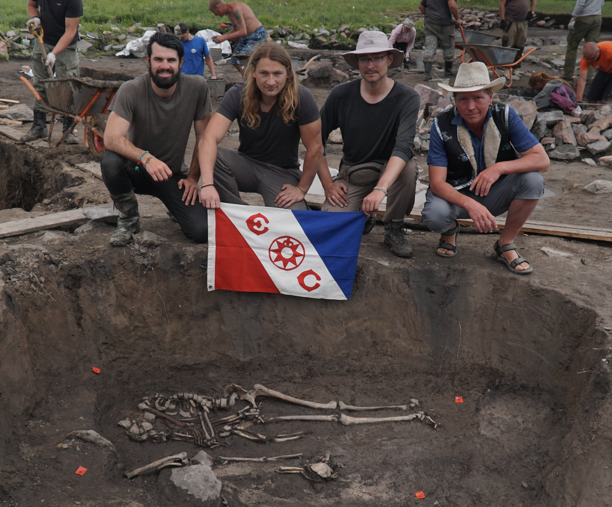 Trevor, Gino, Jegor and Timur with Explorers Club Flag #134 in front of a quadruple burial dating back 1,700 years. Here you see an adult embracing a child. They were surrounded by iron arrowheads and knives.